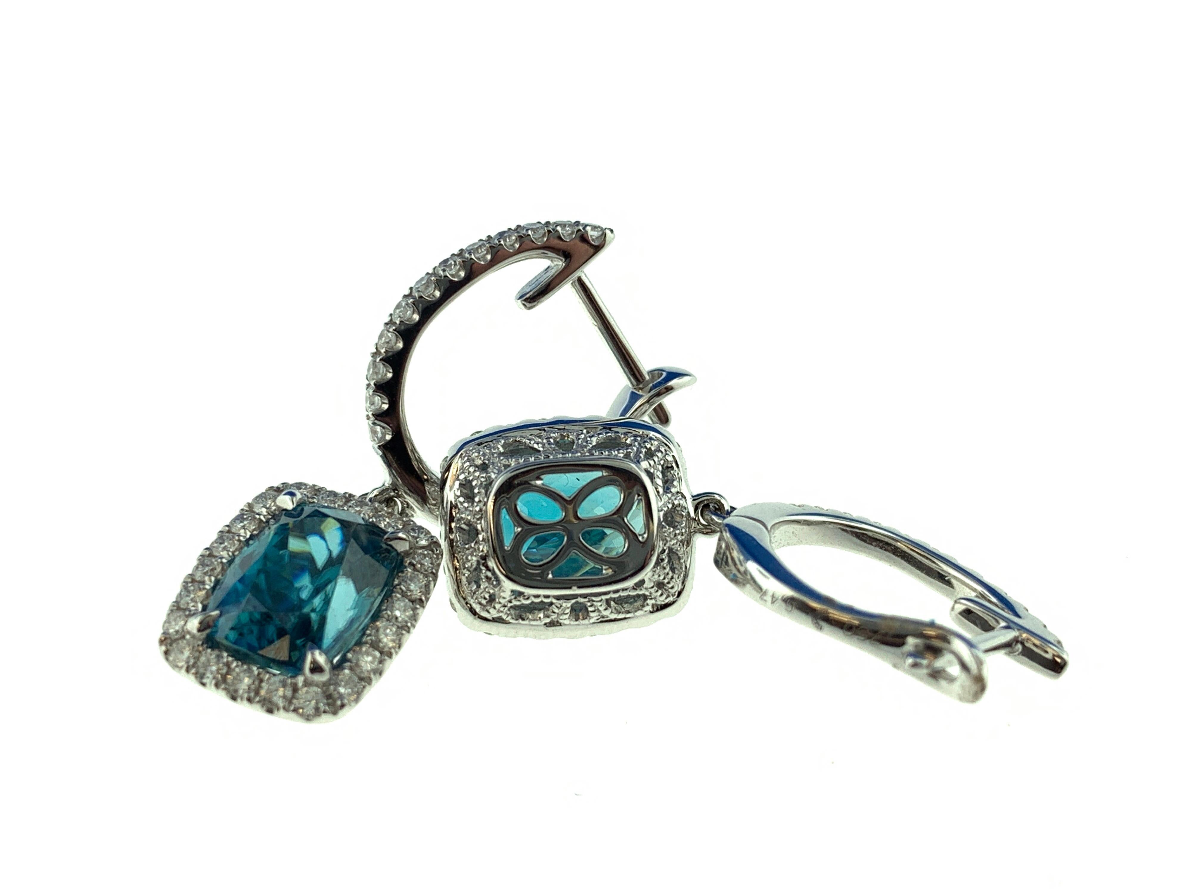 Questi splendidi orecchini presentano 2 zirconi blu taglio cuscino da 3,23 carati ciascuno (6,47 carati in totale), circondati da un'aureola di diamanti tondi taglio brillante, appesi a un cerchio di diamanti. Sono incastonati in una montatura in