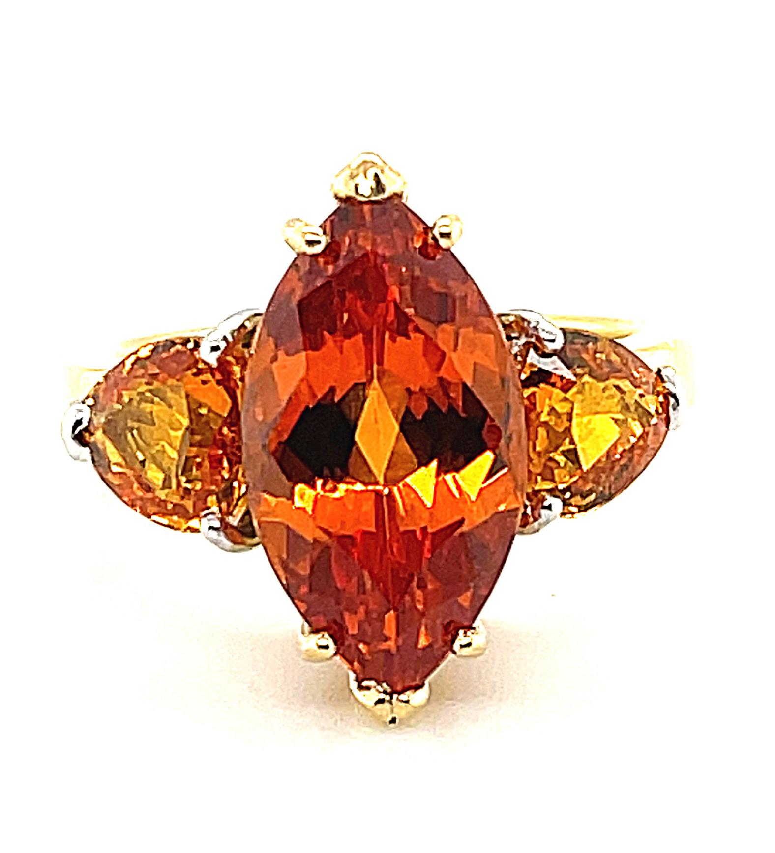 This is a fresh, citrus-colored twist on the classic 3-stone ring! A stunning and exceptionally vibrant Mandarin orange spessartine garnet has been paired with two sparkling trilliant-cut yellow orange sapphires in a head-turning orange-lemon