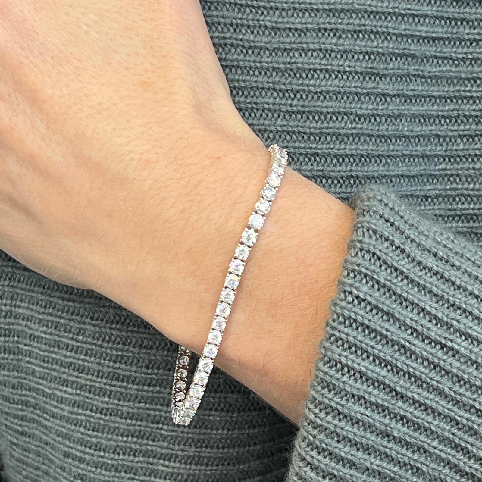 Sparkling diamond tennis bracelet fashioned in 14 karat white gold. The bracelet features 48 round brilliant cut diamonds weighing 6.48 carat total weight and graded G-H color and SI clarity. The bracelet measures 7.25 inches in length, 3.7mm in