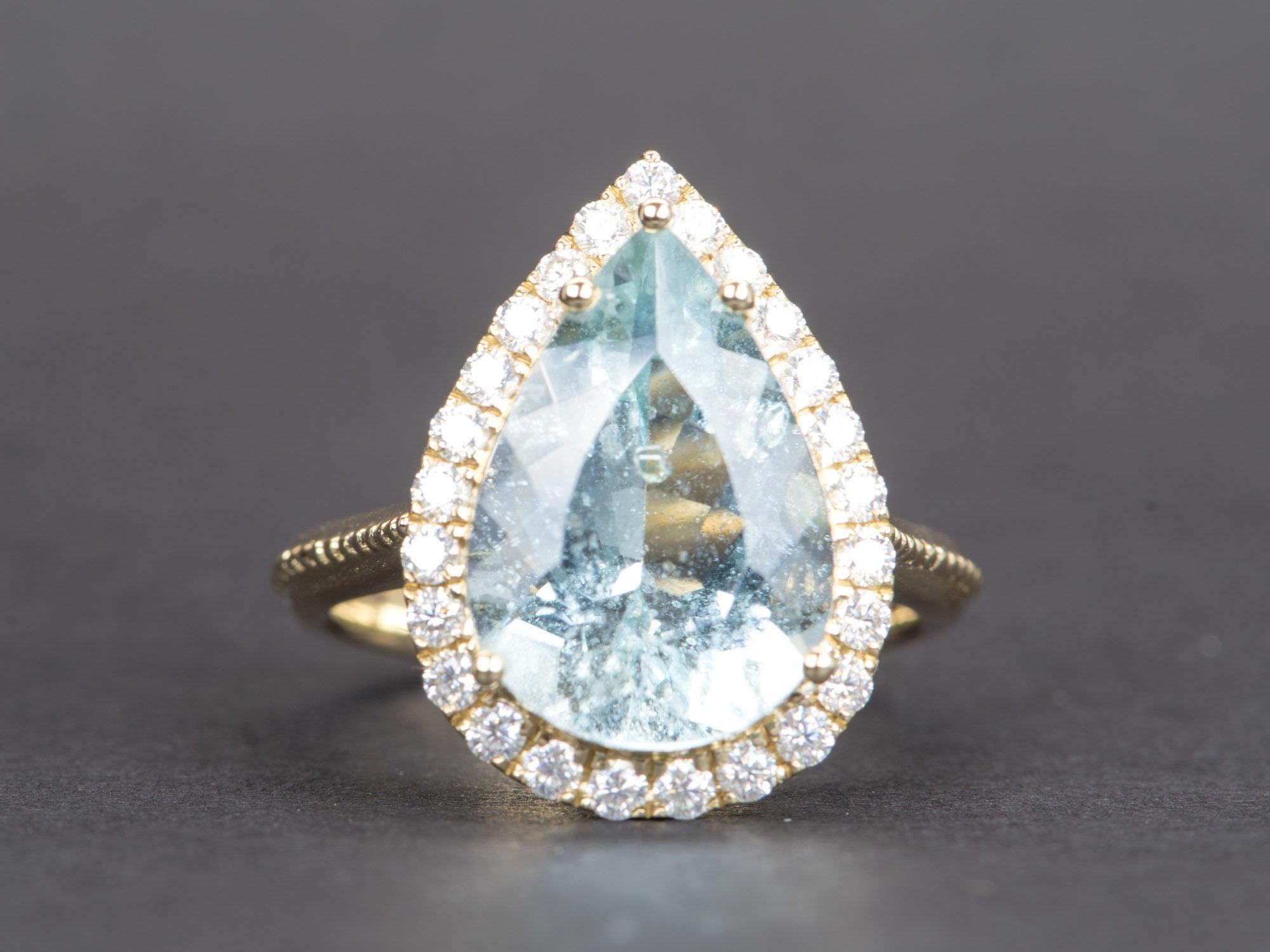 ♥ 6.48ct Statement Galaxy Aquamarine with Moissanite Halo 9K Gold Ring
♥ Solid 9k yellow gold ring set with a beautiful pear-shaped aquamarine
♥ Gorgeous blue color!
♥ The item measures 20.5 mm in length, 15.2 mm in width, and stands 8.4 mm from the