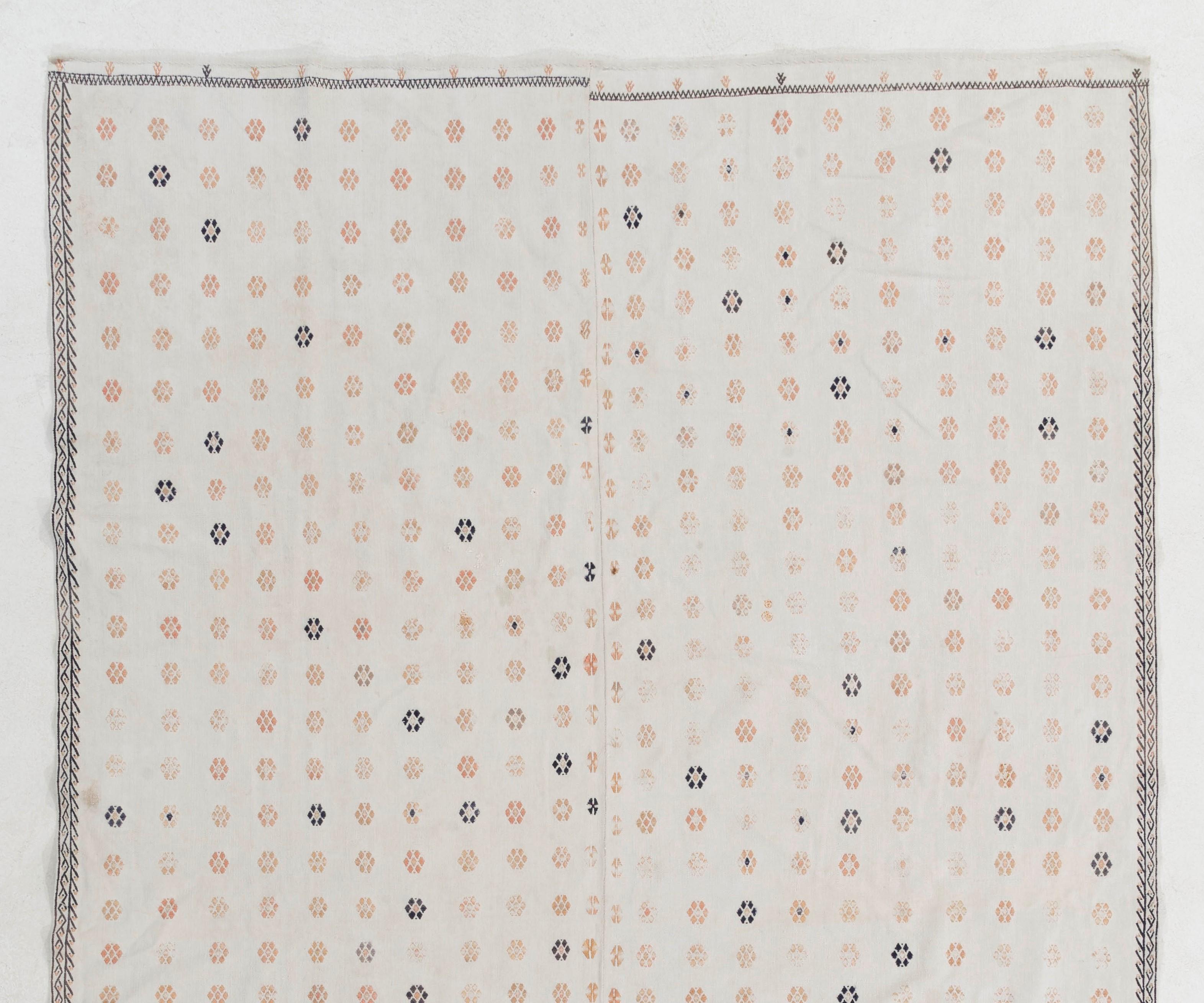 Questo elegante e colorato tappeto kilim vintage è stato tessuto a mano in due pannelli e realizzato in cotone. Presenta un disegno floreale all-over in rosa salmone e blu navy su uno sfondo bianco sporco. È in buone condizioni, robusto e pulito