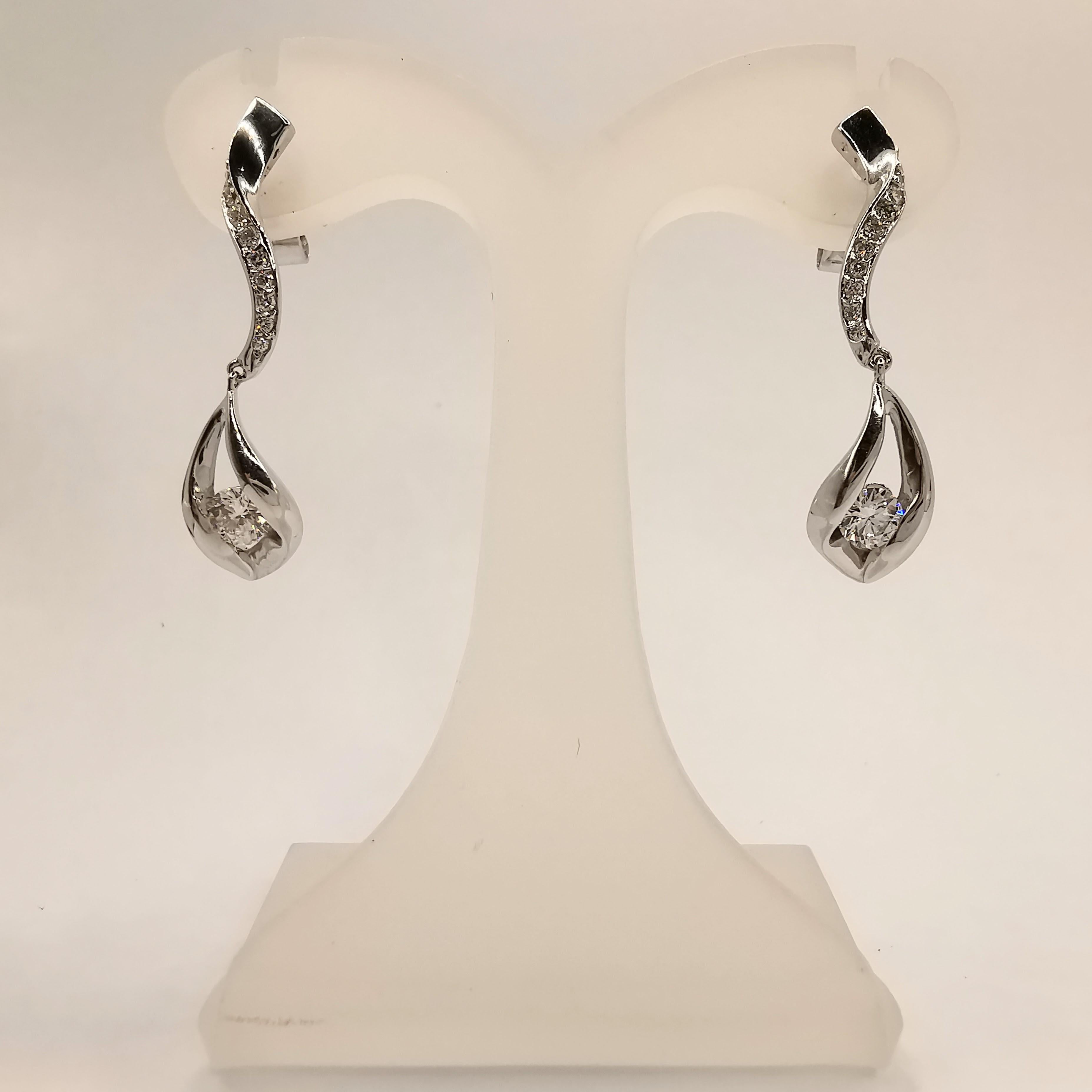 Add a touch of elegance and sophistication to any look with these stunning .65 Carat Diamond Drop Earrings in 18K White Gold. The earrings feature a stylish curve design, creating a modern and eye-catching appearance. The dazzling diamonds are the