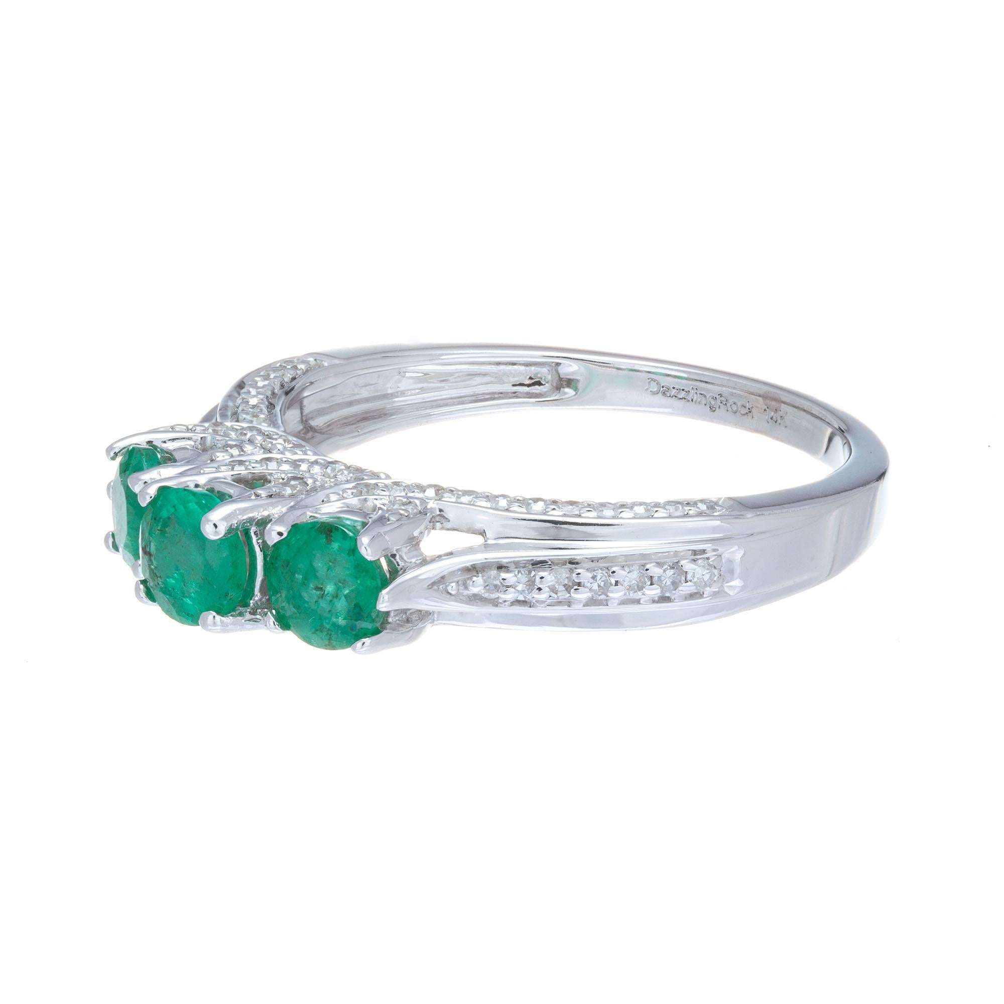 Emerald three-stone ring with three bright green emeralds in curved prongs with 78 diamond accents in 14k white gold. 

3 round green emeralds, approx. .65cts
78 single cut diamonds H-I SI, approx. .58cts
Size 7 and sizable 
14k white gold 
Stamped: