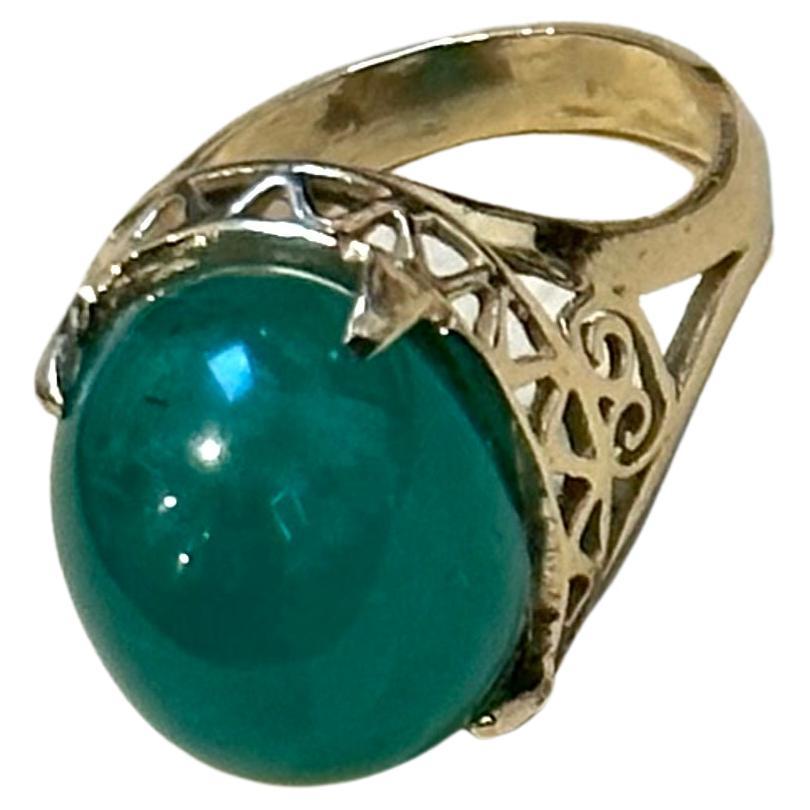 This classic cocktail ring is a stunning piece of jewelry that features an approximately 6.5 carat natural emerald cabochon. The estate piece has not undergone any color enhancement and is made of 14 karat yellow gold, stamped and weighing 6.6 grams