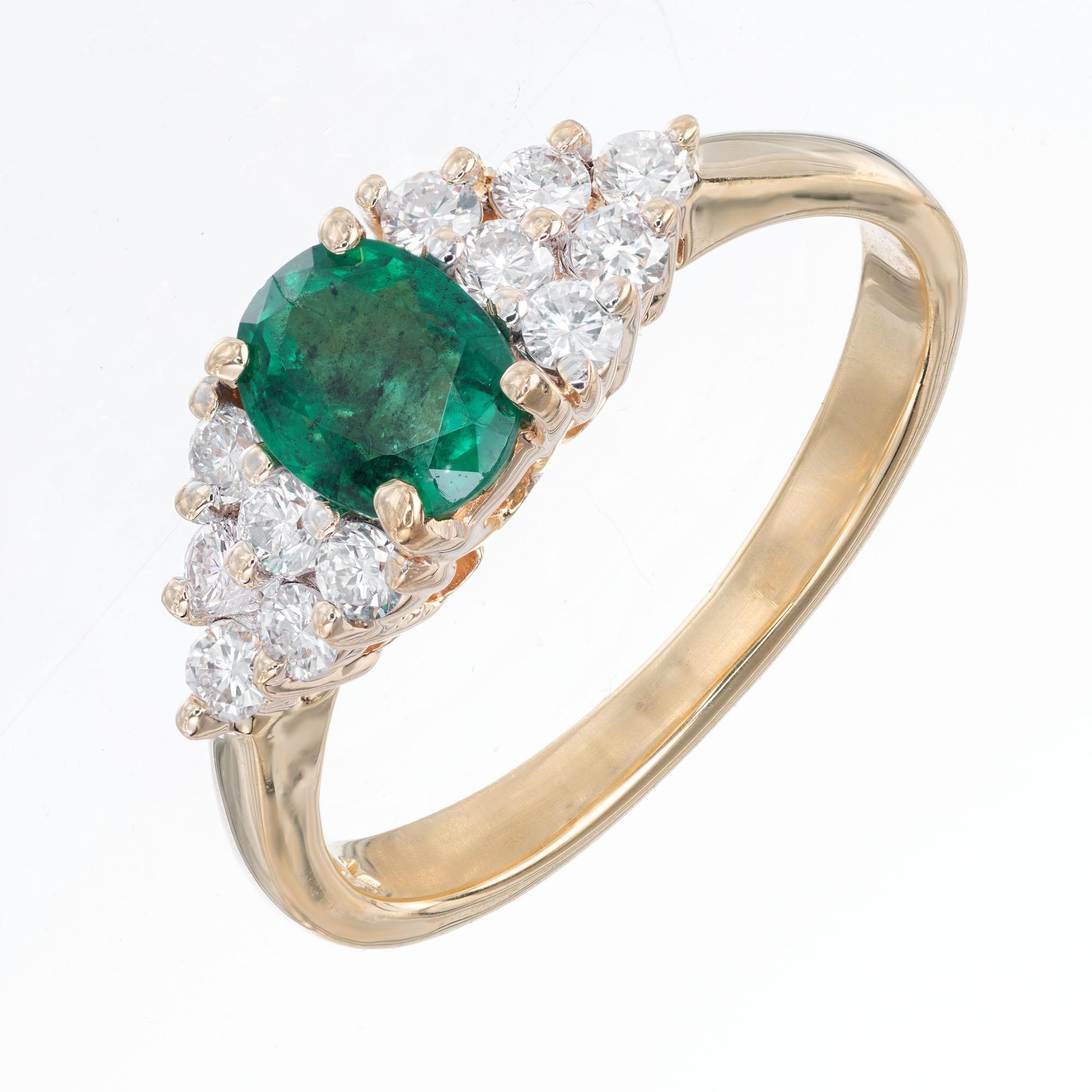 Emerald and diamond engagement ring. .65cts center oval emerald with triangle of 6 clustered diamonds on each side, in a 14k yellow gold setting. 

1 oval emerald .65cts, 6.2 x 4.9mm approx. total weight .65cts
12 round diamonds approx. total weight