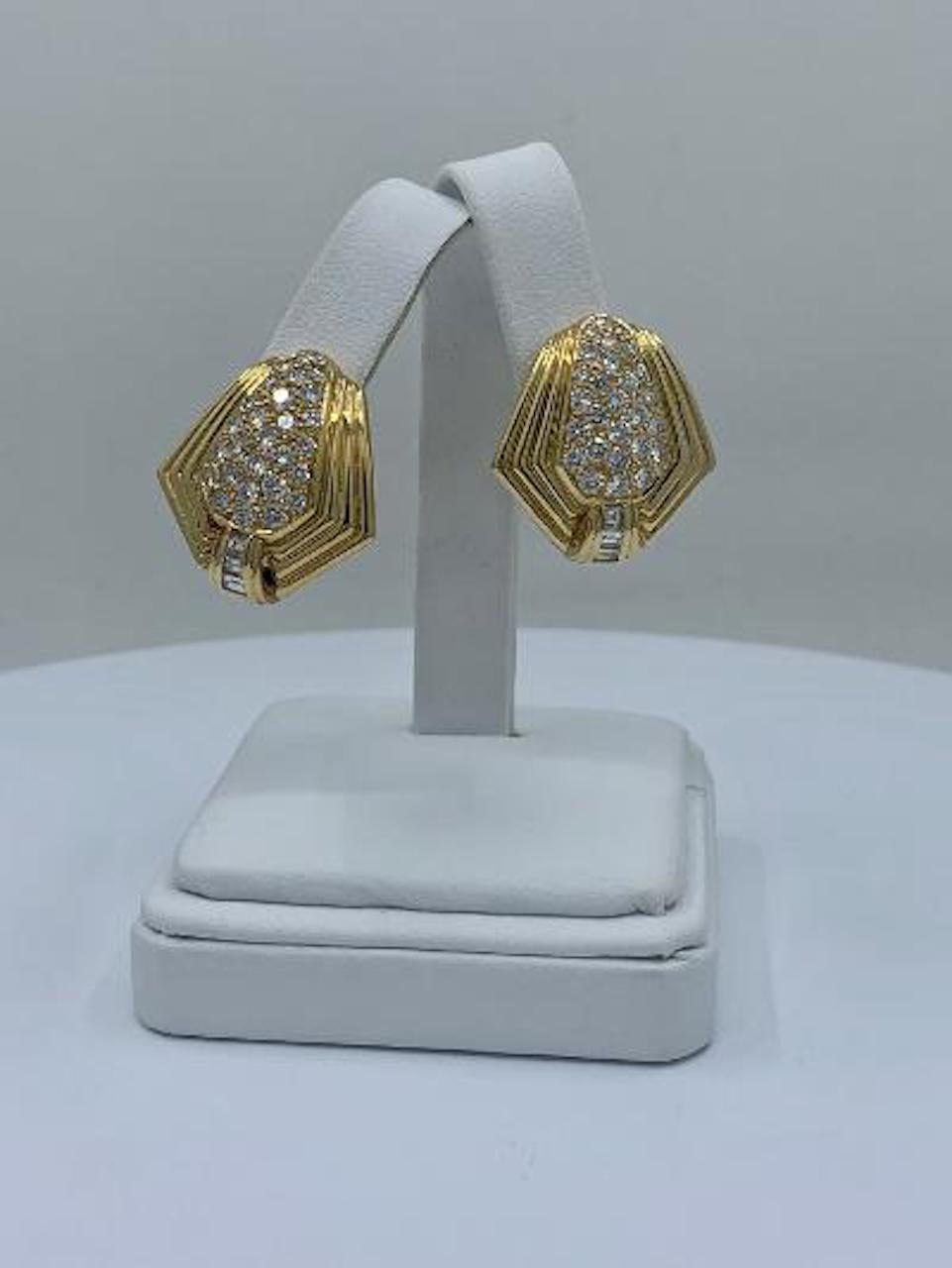 Very elegant, pair of custom hand made, 18 karat yellow gold Art Deco angular design diamond clip on earrings feature 28 pave set round brilliant diamonds in each earring that are accented on the bottom with three baguette diamonds that graduate in