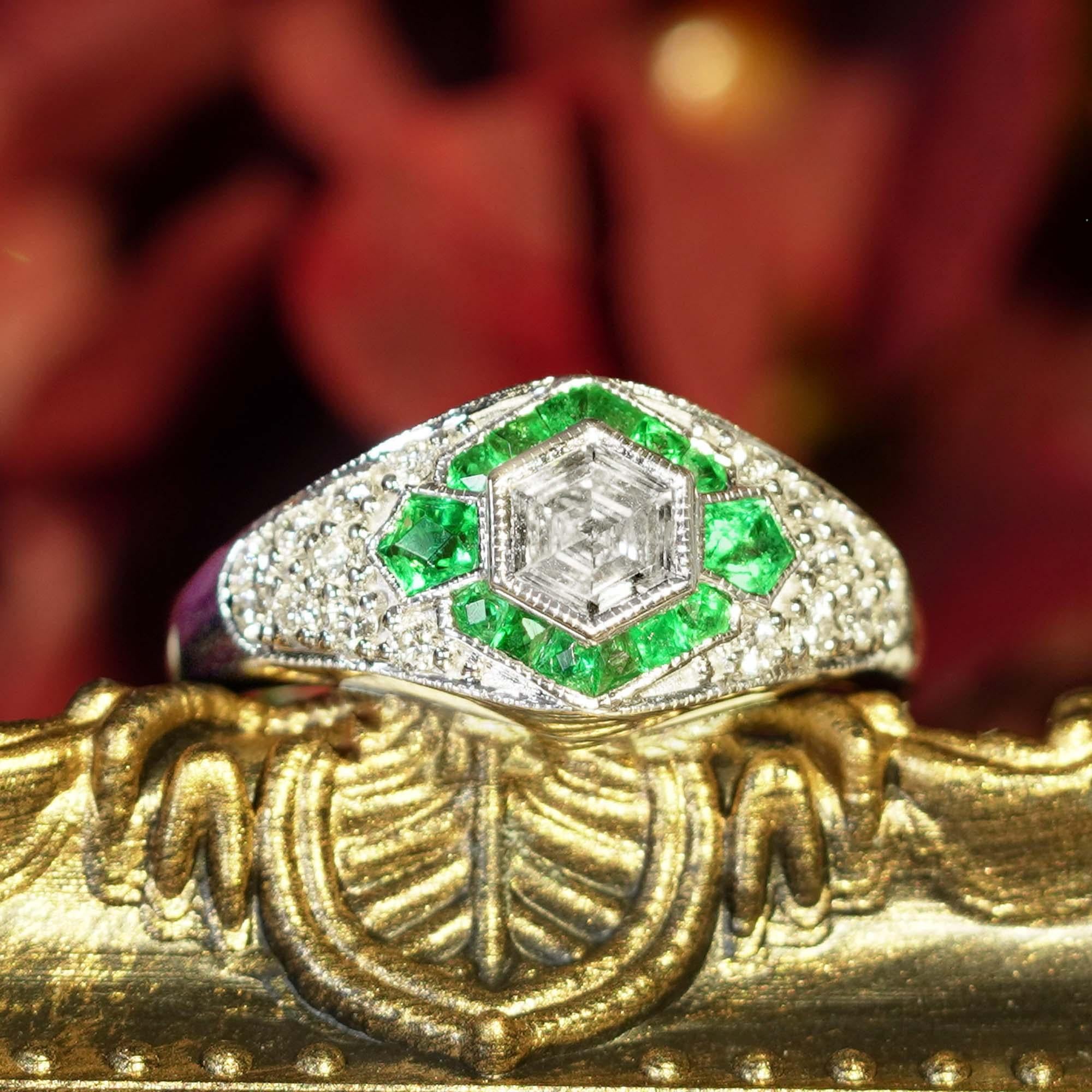 A uniquely beautiful Art Deco inspired diamond engagement ring featuring an entrancing and enchanting hexagonal cut diamond weighing about .65 carat. This rare and radiant rick is set in milgrain bezel surrounded by French cut emerald  and diamond