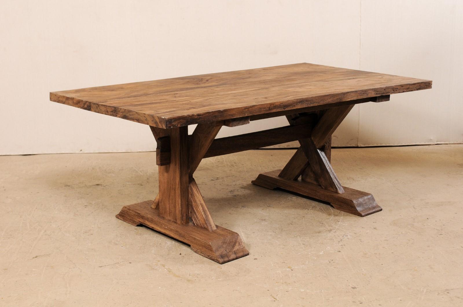 A vintage trestle table with x-frame base of reclaimed wood. This trestle-style table has been made of reclaimed Indonesian wood, a sturdy tropical hardwood, having a rectangular-shaped top which is raised by a pair of trestle legs, with x-shaped