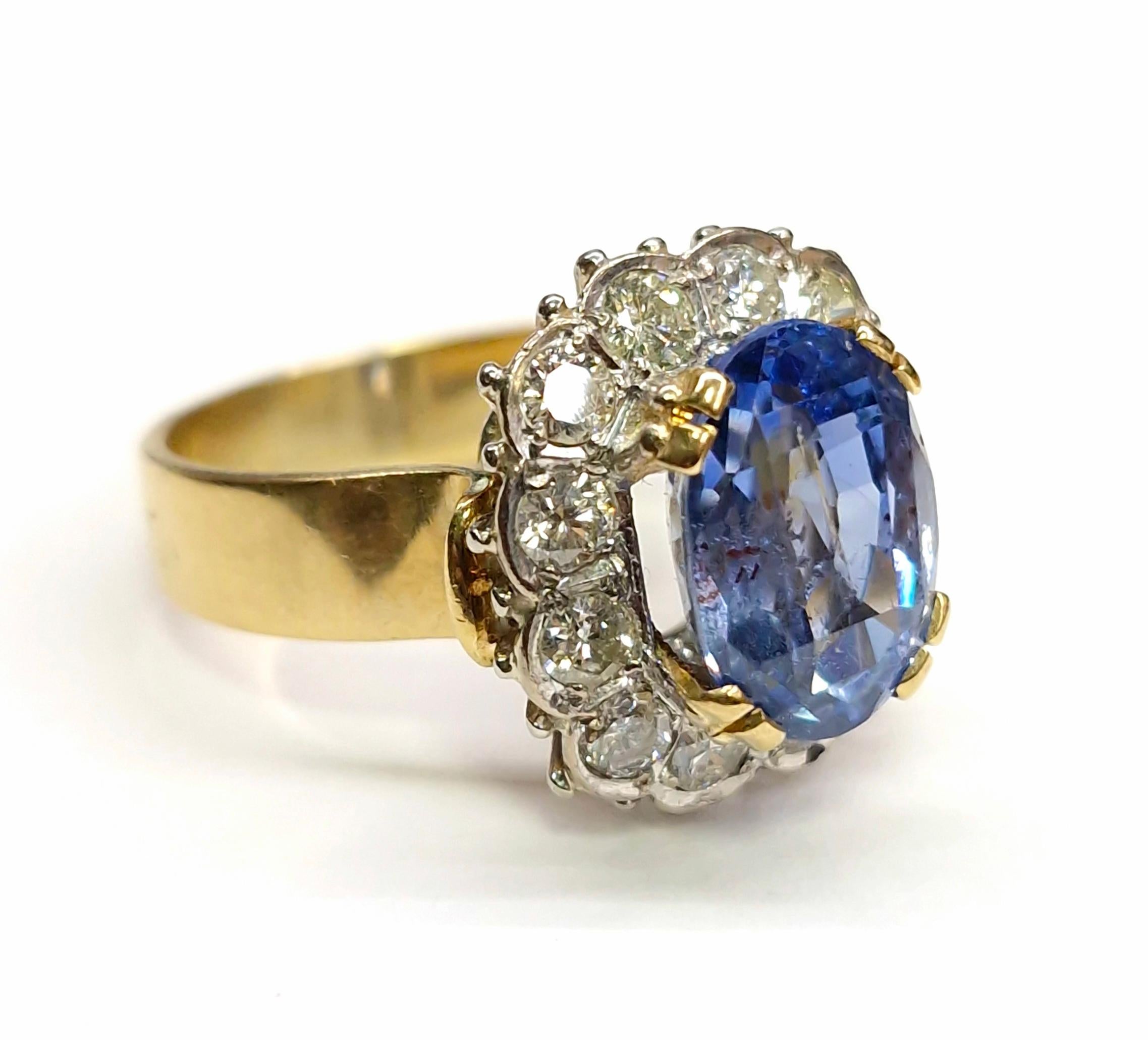 Anello con zaffiro, 6,50 carati, anello con diamante, 1,10 carati, oro giallo e bianco 18 carati, anello con zaffiro aureolato taglio ovale. Questo squisito anello bicolore è realizzato magistralmente in oro giallo e bianco da 18 carati. Al centro
