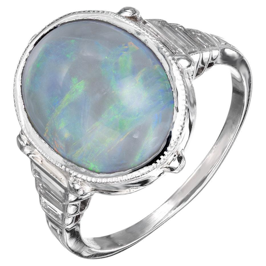 Opal and diamond ring. Translucent silvery black natural oval opal with flashes of green, blue, yellow and orange in a platinum setting with 6 emerald cut accent diamonds. 

1 oval cabochon natural black opal approx. total weight 6.50cts
6 emerald