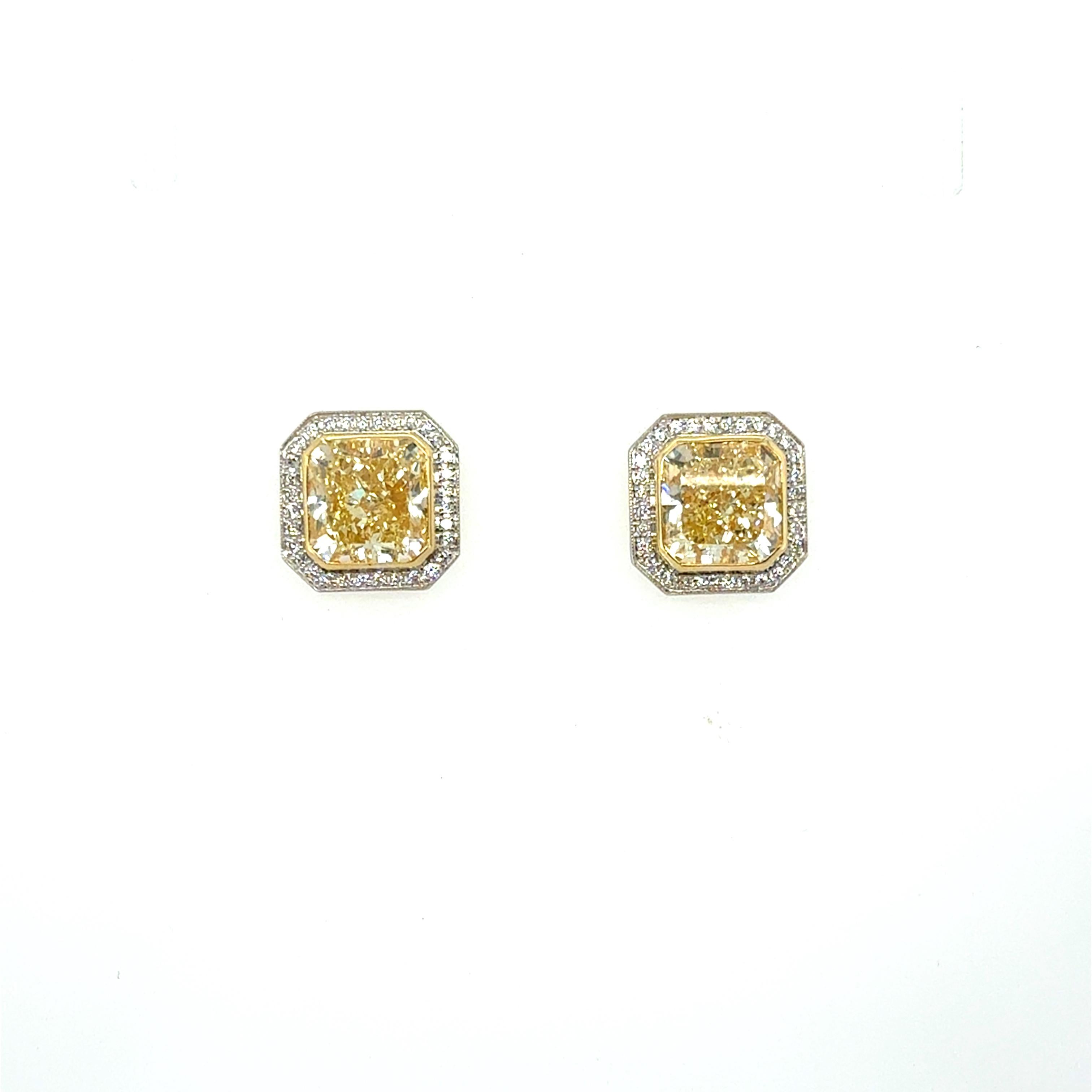 Exquises boucles d'oreilles en diamant jaune clair présentant deux magnifiques diamants jaune clair pesant 6,50 carats au total, chacun entouré d'un halo de diamants ronds de taille brillant pesant environ 0,64 carat au total. Réalisés avec soin en