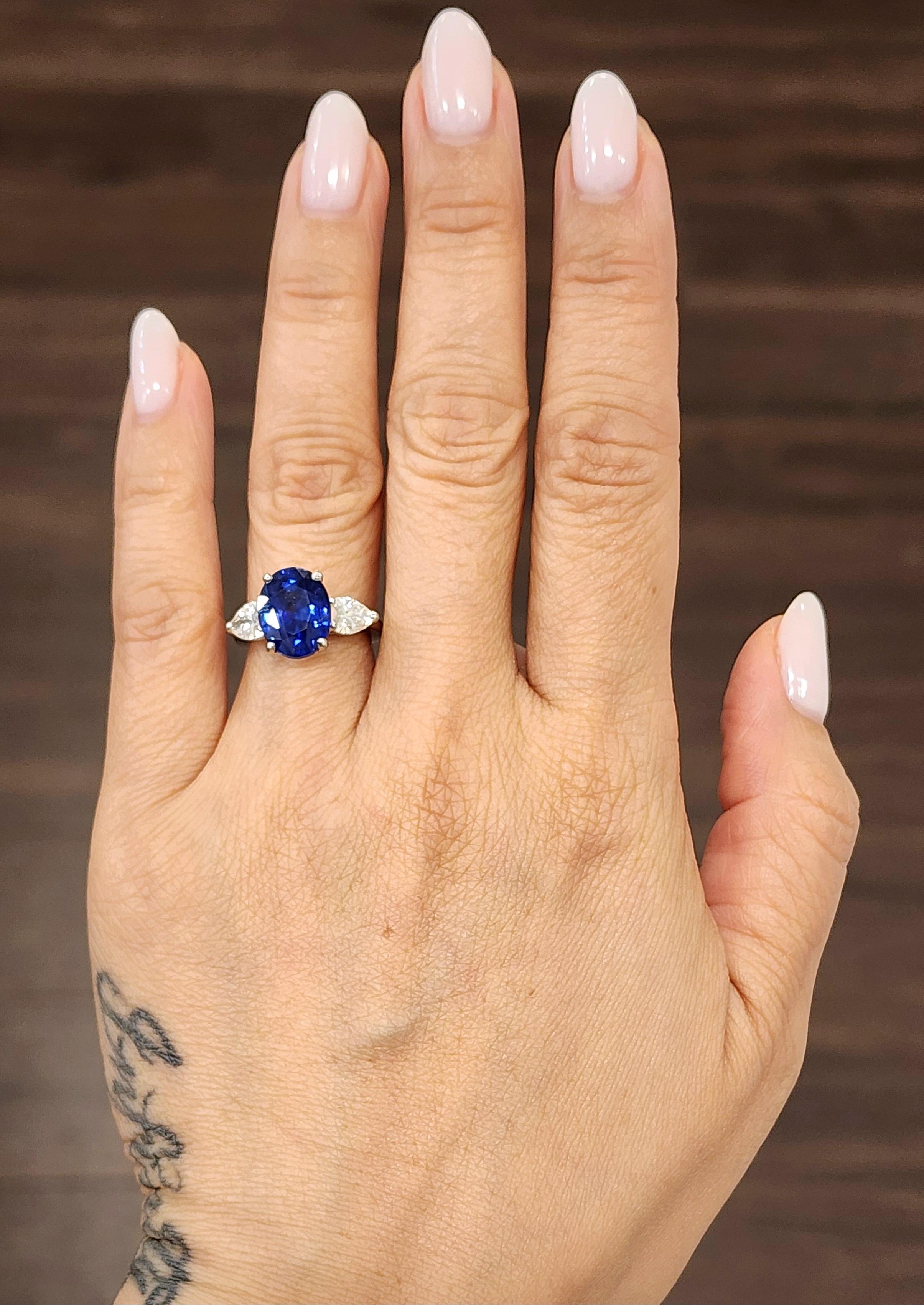 This exquisite cocktail ring features a captivating 5.42-carat oval blue sapphire as its centerpiece, set in luxurious platinum. Flanking the sapphire are two pear-cut white diamonds, totaling 1.09 carats, with an F/G color grade and VS1/VS2