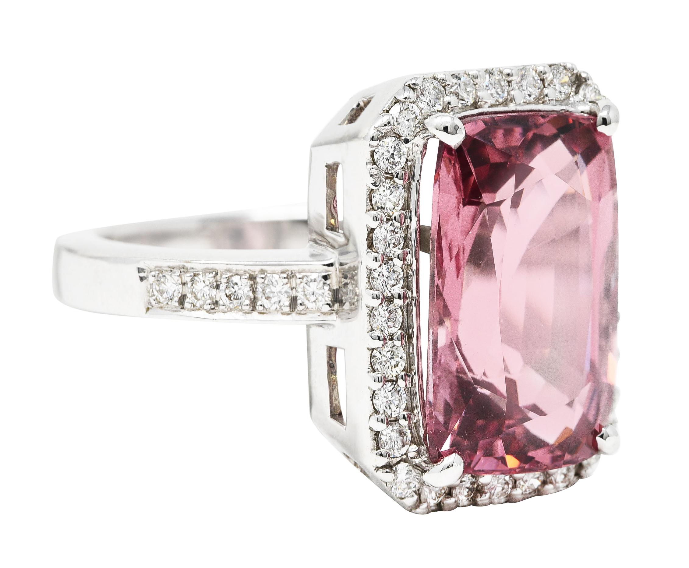 Centering and elongated cushion cut spinel weighing approximately 6.12 carats total. Transparent brownish-pink in color with light to medium saturation. Prong set with a halo surround of round brilliant cut diamonds. Bead set with additional