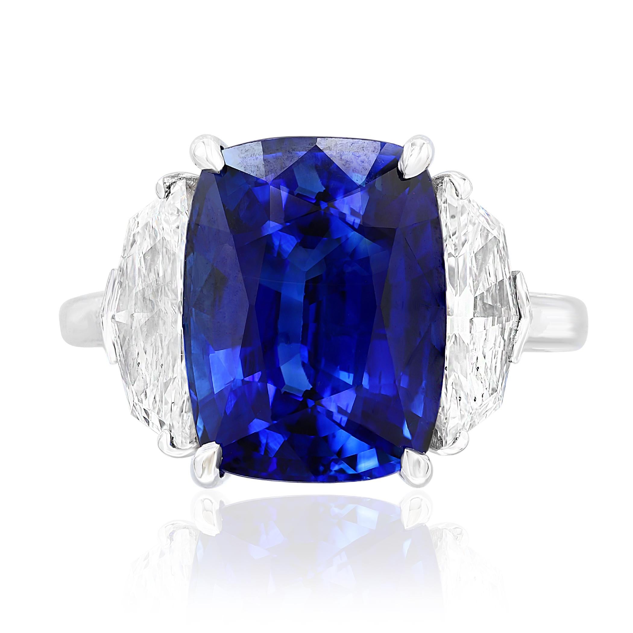 Showcases a Cushion cut, Vibrant color Blue Sapphire weighing 6.54 carats, flanked by two brilliant cut half moon diamonds weighing 1.24 carats total. Elegantly set in a polished platinum composition.