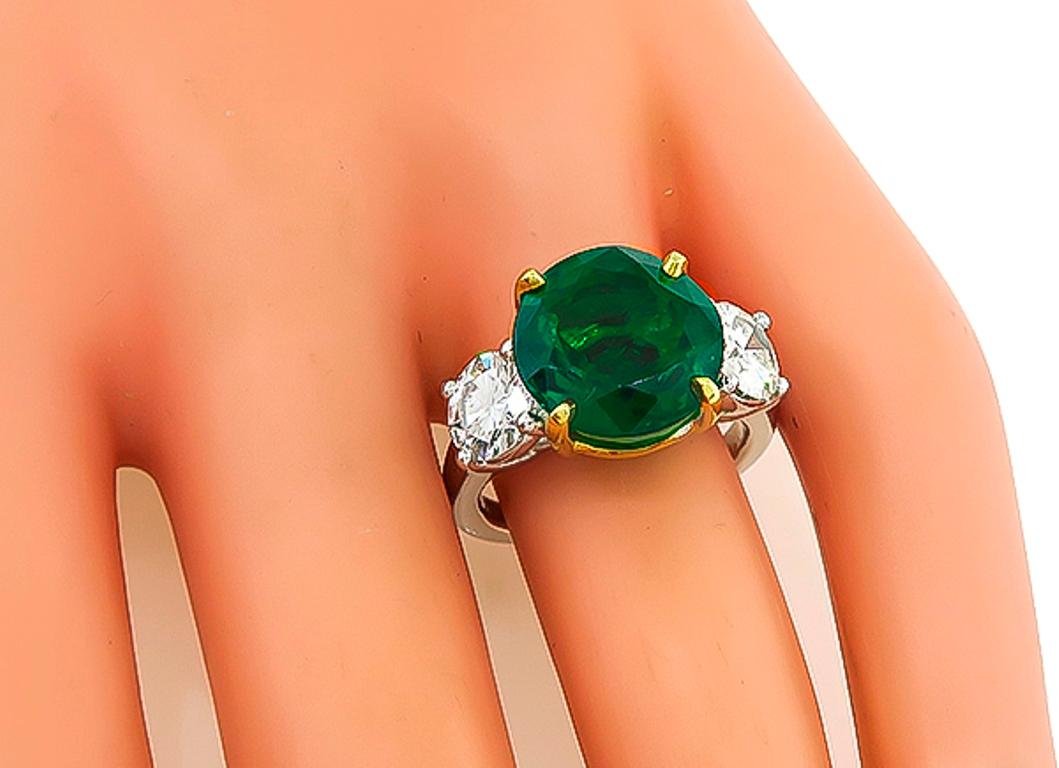 This gorgeous platinum anniversary ring is centered with lovely round cut emerald that weighs 6.54ct. The emerald is accentuated by two sparkling GIA certified round brilliant cut diamonds that weighs 0.76ct and 0.80ct. The color of the diamonds is