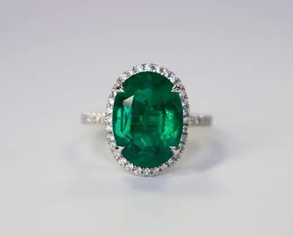 Emerald Weight: 6.55 ct, Measurements: 14x10 mm, Diamond Weight: 0.33 ct, Metal: 18K White Gold, Gold Weight: 4.92 gm, Ring Size: 6.5, Shape: Oval, Color: Vivid Green, Hardness: 7.5-8, Birthstone: May, Origin: Zambia