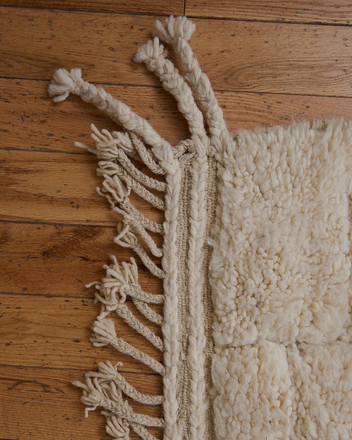 The Inez rug is a beautiful Beni Ouarain piece, handwoven by Berber artisans in the Atlas Mountains of Morocco. Featuring a soft cream background, this rug showcases classic minimalist geometric patterns, a hallmark of traditional Beni Ouarain