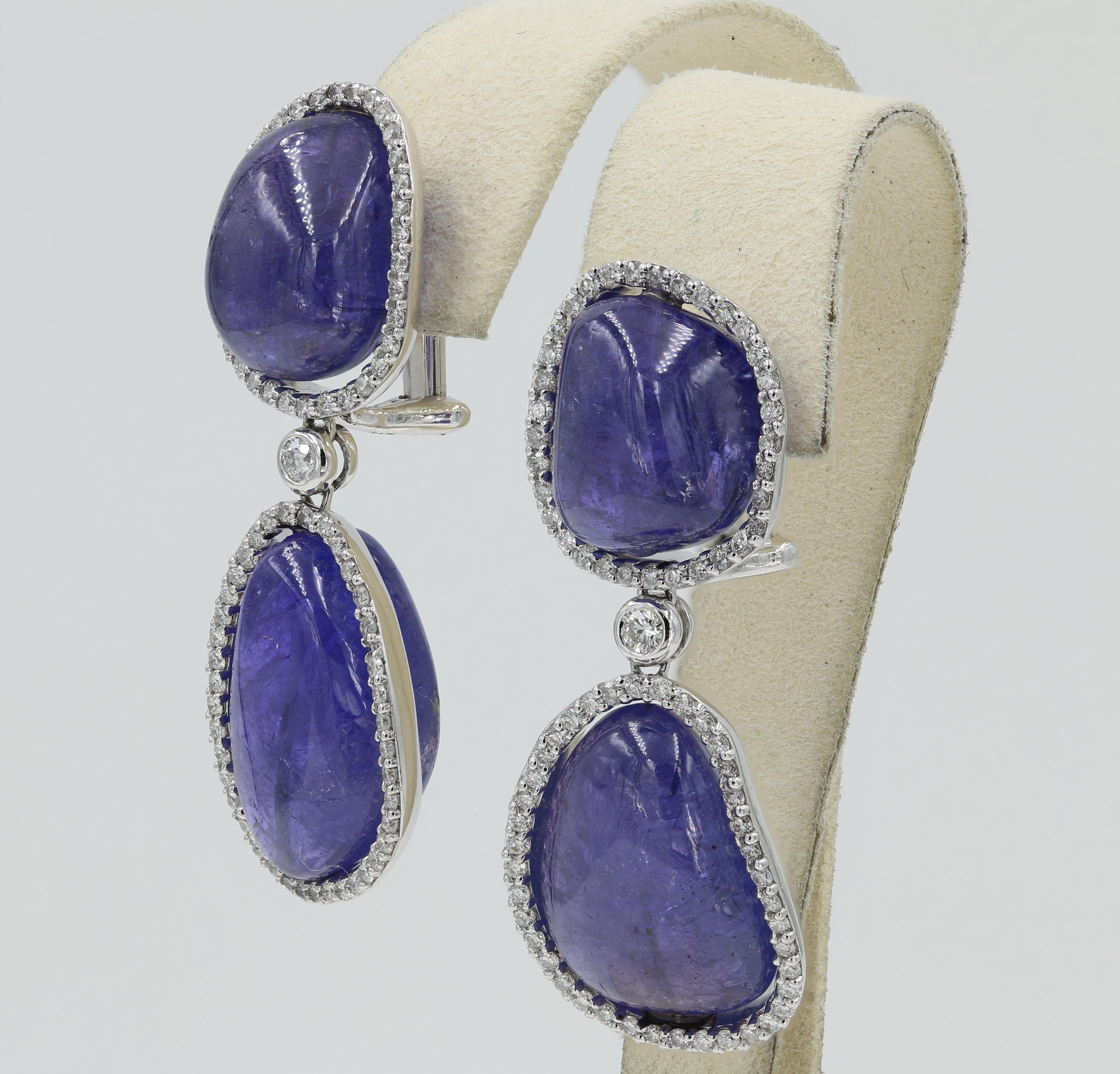 These beautifully drop style earrings have 4 Tanzanite Cabochon cuts weighing approximately 65.50cts. total. 150 Round Diamonds weighing 1.40cts. total delicately frame each cabochon. 

Earrings are finished in 18kt.white gold and Omega clip style