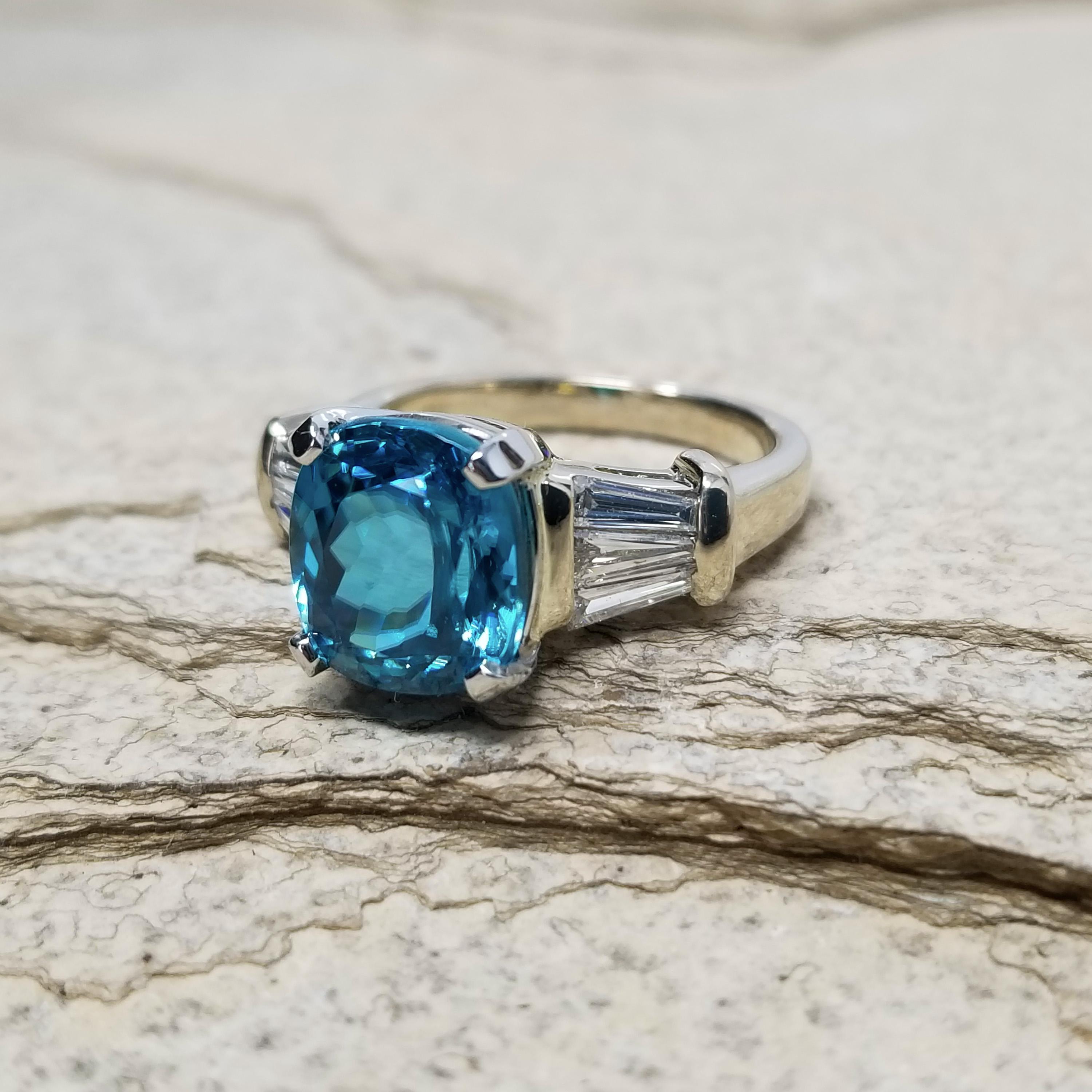 Ce zircon bleu du Cambodge a été taillé pour maximiser la brillance inhérente au zircon, et le résultat est absolument scintillant. Cette pierre précieuse éblouit par son riche bleu turquoise.

Cette bague en diamant est d'un style intemporel ; elle