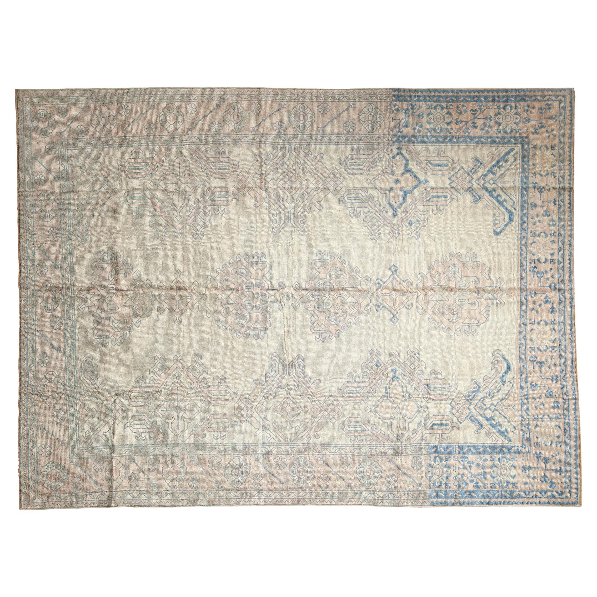 :: Classico Oushak a campo coperto con palmette floreali sovradimensionate e foglie reciproche che circondano medaglioni minori. I colori e le sfumature includono: Avorio, rosa pallido, azzurro, blu denim e altri ancora. Note di condizione: Usura