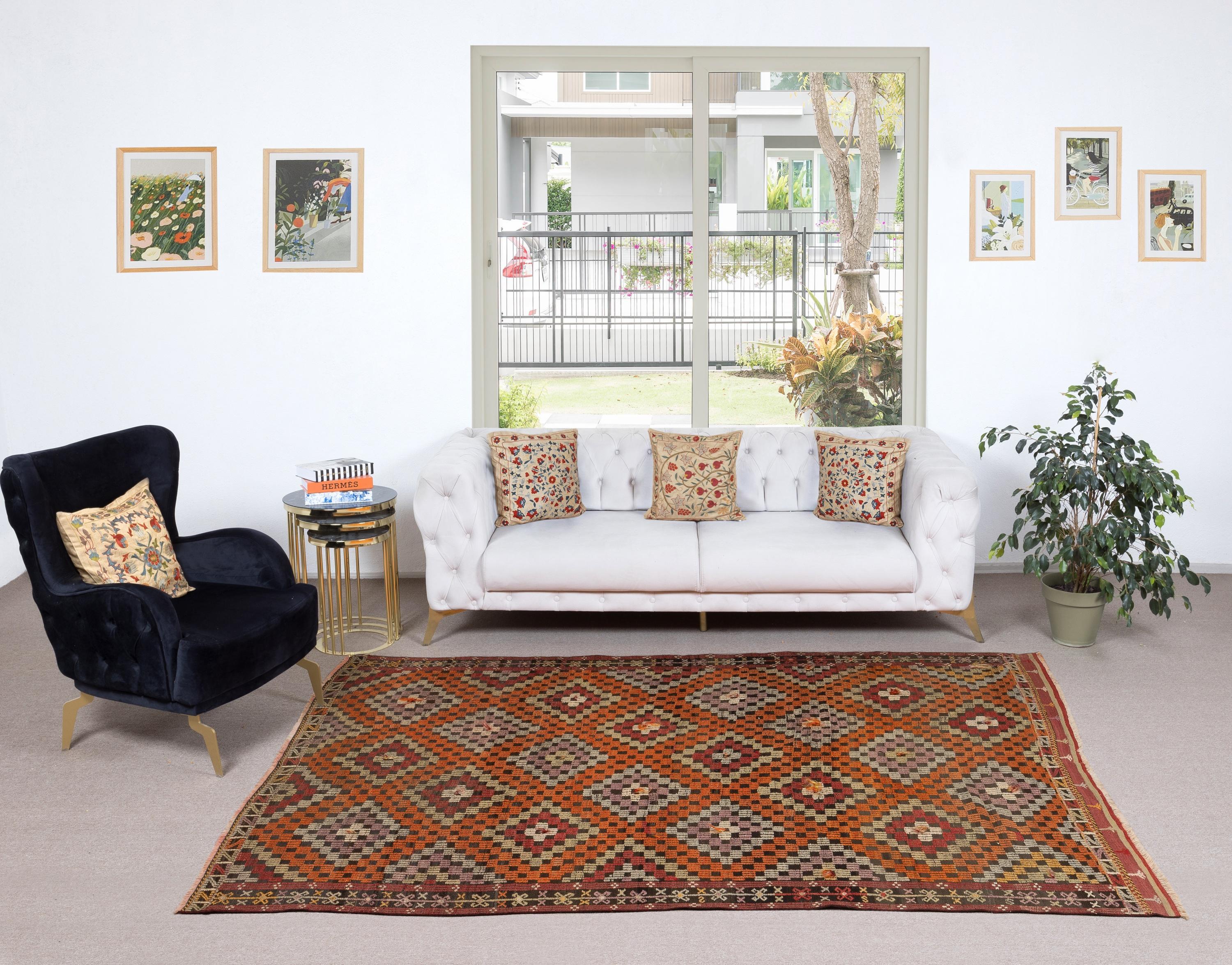 Aggiungi carattere e tradizione alla tua casa con questo tappeto vintage turco Jijim Kilim, uno splendido tappeto a tessitura piatta realizzato a mano in lana naturale al 100%. Realizzato a metà del XX secolo nella Turchia centro-meridionale con