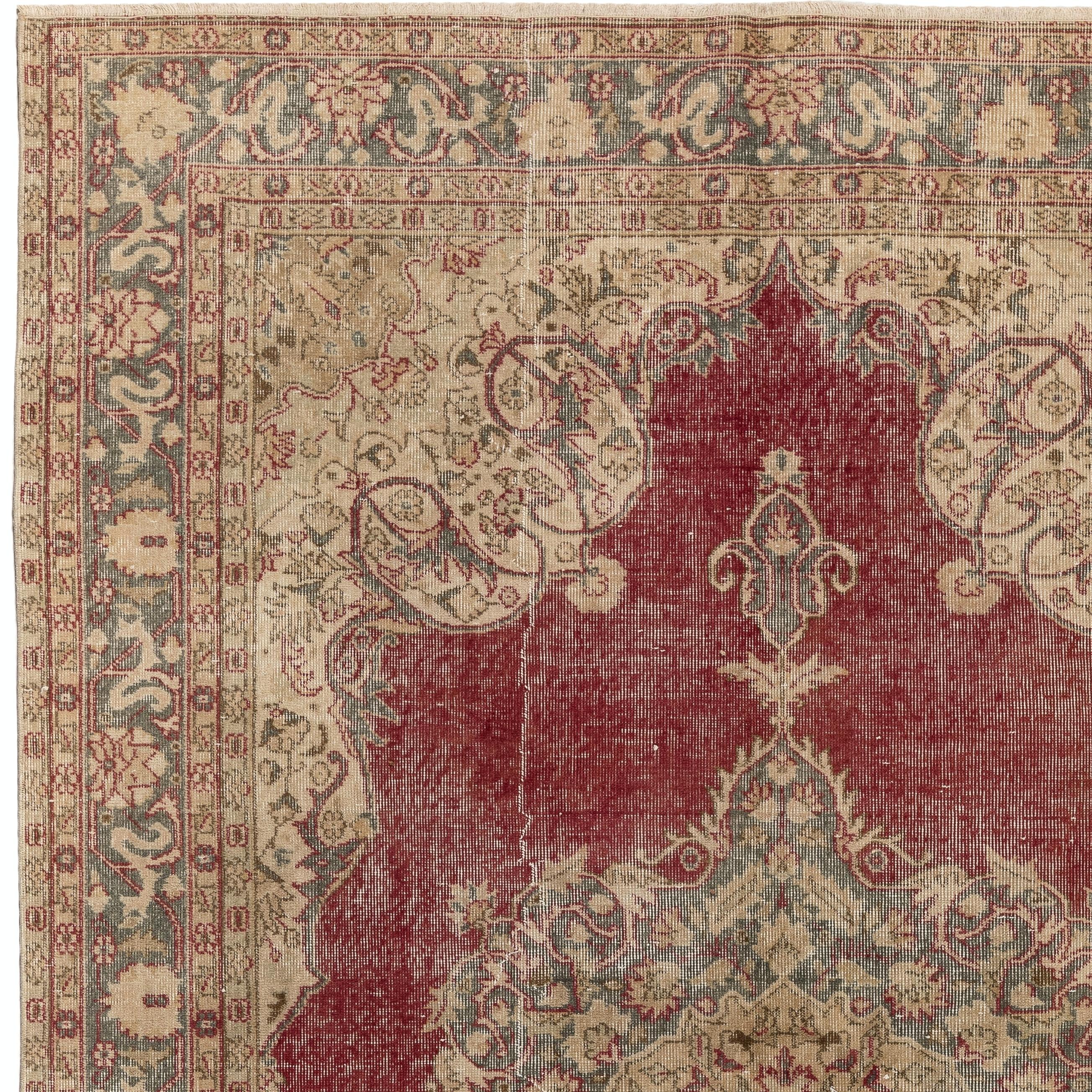 A beautiful hand-knotted Turkish Oushak rug from the 1960s featuring an elegant central medallion on a burgundy red field as well as lush arabesque corner pieces and borders in beige and greenish gray, decorated with palmettes and scrolling leafy