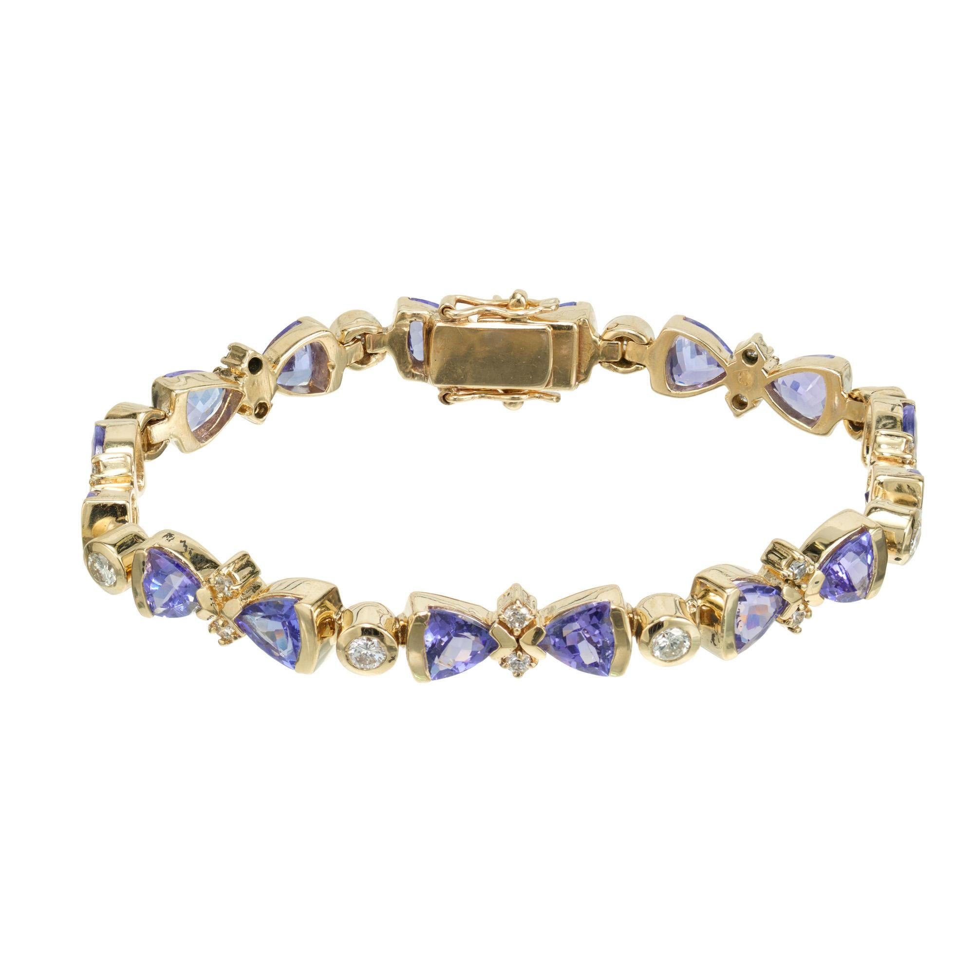 1970's Tanzanite and diamond link bracelet. 16 triangular purple blue semi bezel set tanzanite's totaling 5.60cts. separated by 24 round bezel set diamonds totaling 1.00cts in 14k yellow gold. The bracelet measures 7 inches and is secured with a