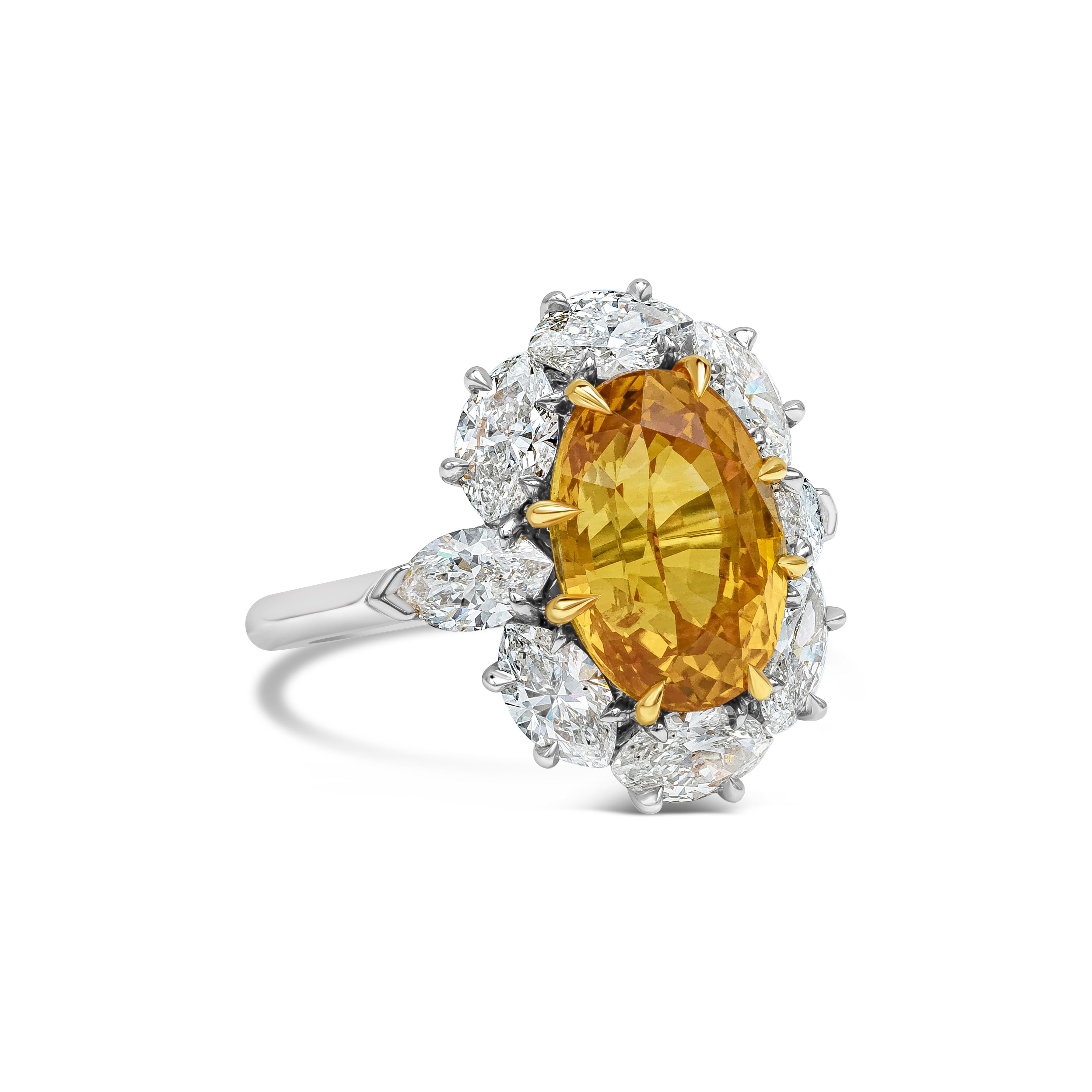 A color rich gemstone halo ring showcasing a GIA Certified oval cut orange sapphire weighing 6.64 carat total set in an eight prong 18K yellow gold setting. Surrounded by eight GIA certified marquise cut diamonds in a halo design weighing 2.42