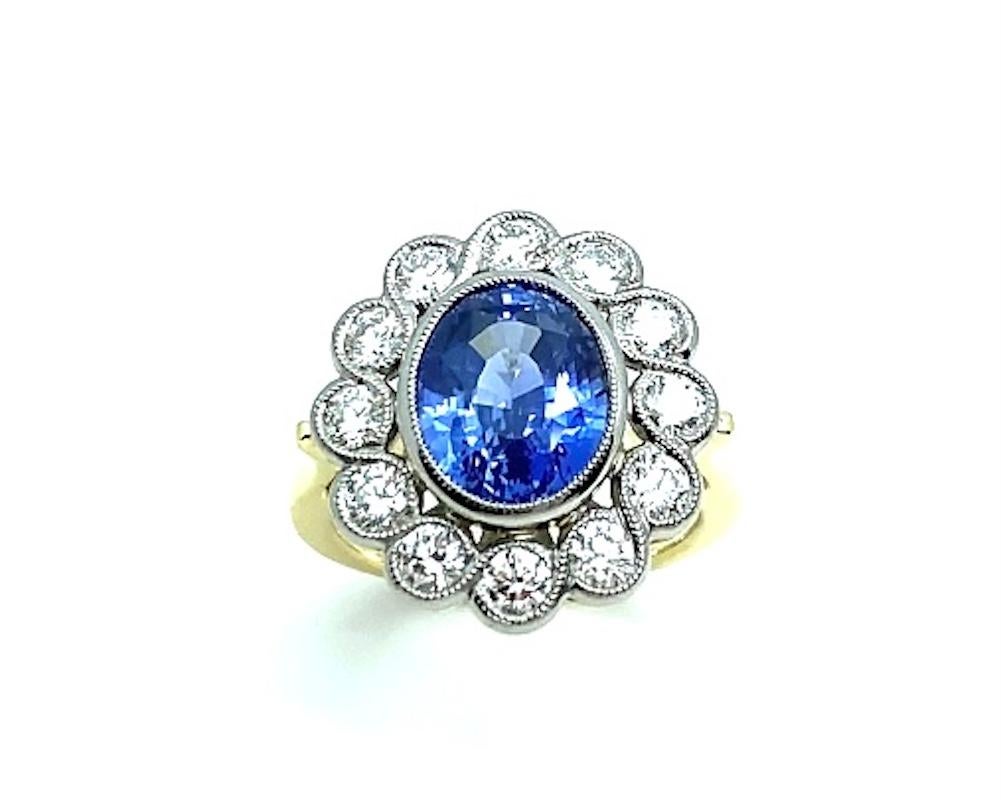 A brilliant, 6.67 carat cornflower blue sapphire sits center stage in this spectacular 18k white and yellow gold cocktail ring. The sapphire is a bright, lively stone with a gorgeous shape that is highlighted by a white gold bezel. Surrounding the