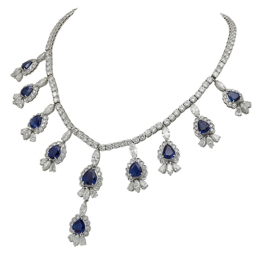 A fashionable and elegant earrings and necklace set that is perfect for an important event or gala. The earrings have a dangle design and consists of pear shape blue sapphires set in a brilliant diamond halo. Suspended on the halos are three pear