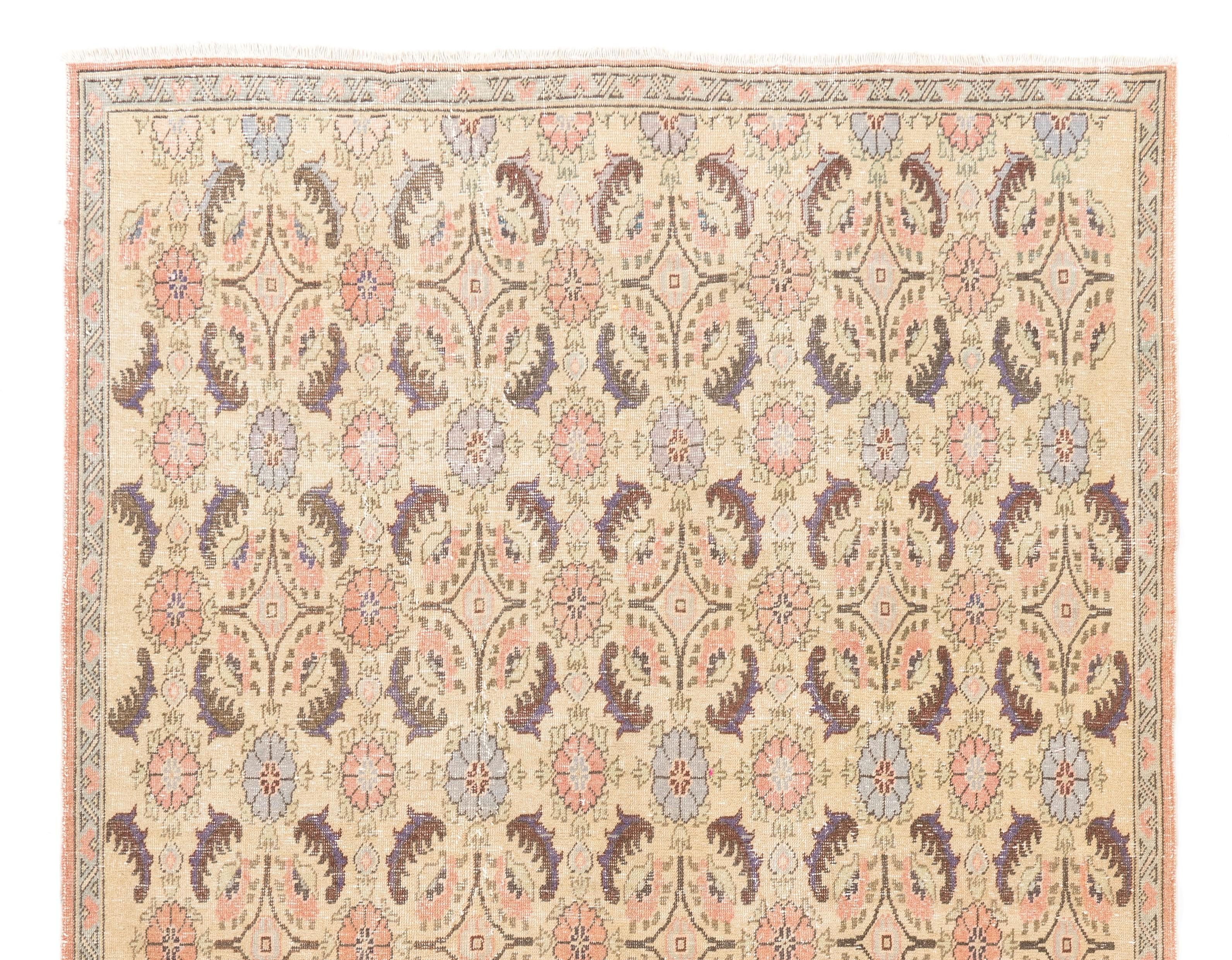 A mid-20th century hand-knotted Turkish rug with an elegant art deco floral design in a soft, pastel color palette of beige, coral pink and light blue. The rug has low wool pile on cotton foundation, is in well-preserved condition, sturdy,