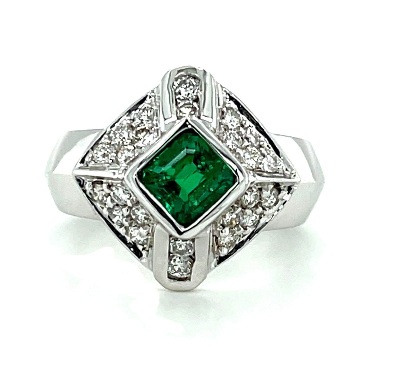 Reminiscent of the Art Deco period and timeless in design, this emerald and diamond ring is simply dazzling! The center emerald weighs .67 carat and is a top quality, vibrant, rich green color. It has been set at an angle in a bright, high-polished