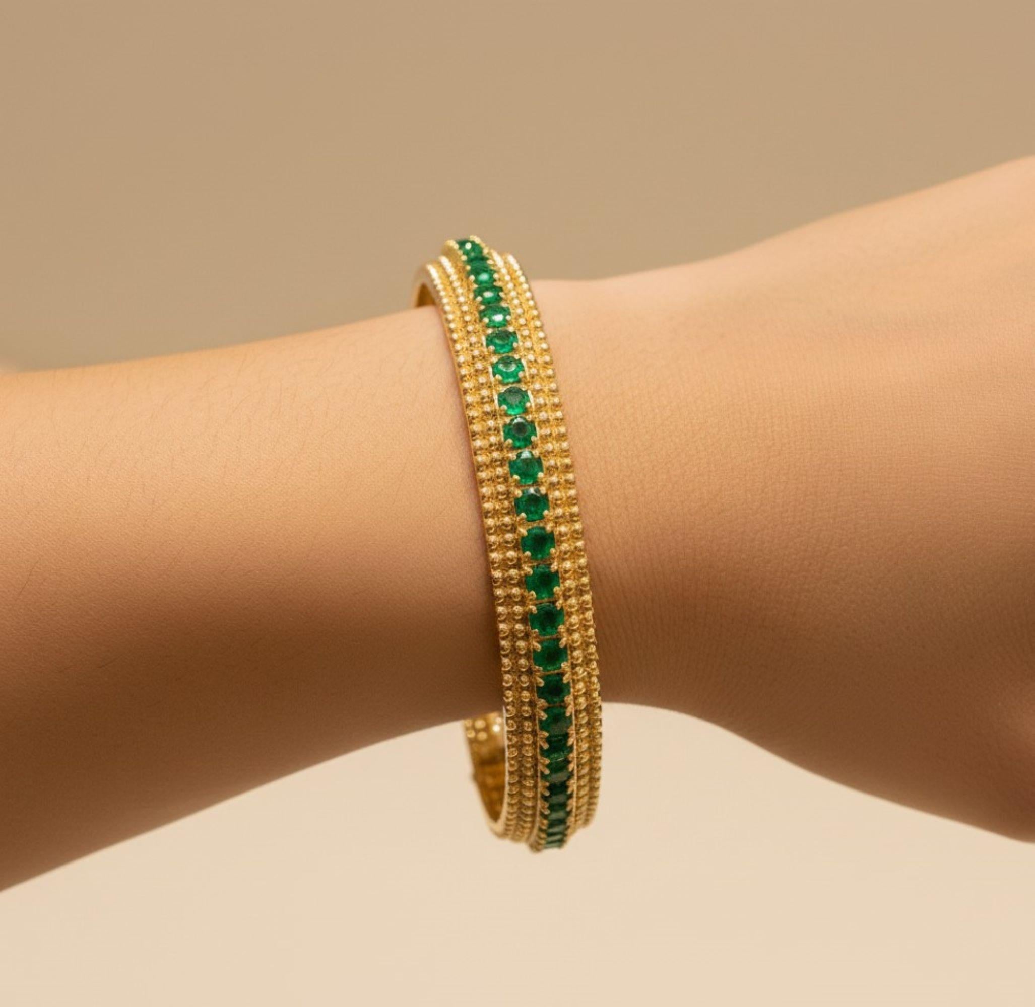 Handmade Milgrain Edged Emerald Bangle 6.75 Carat 14 Karat Yellow Gold Jewelry 
It features a moderately wide band composed of two or three distinct rows that run parallel to each other. The dividing lines and the edges of the bracelet are covered