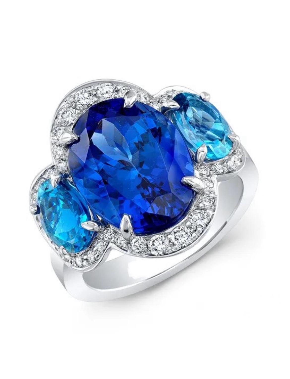 A delightful 6.70-carat Tanzanite is graciously supported by two aquamarines weighing 1.44 carats, accented by numerous shimmering white diamonds totaling 0.49 carats, fabricated in 18K white gold. 