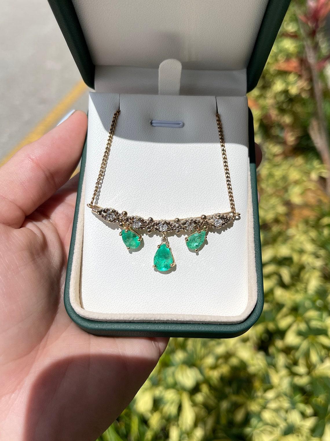 A vintage, medium-rich green pear Colombian emerald and diamond necklace. Handcrafted in solid 14k yellow gold, the vintage piece showcases three beautiful Colombian emerald pears that are nestled in a 4 prong setting. Each stone is completely