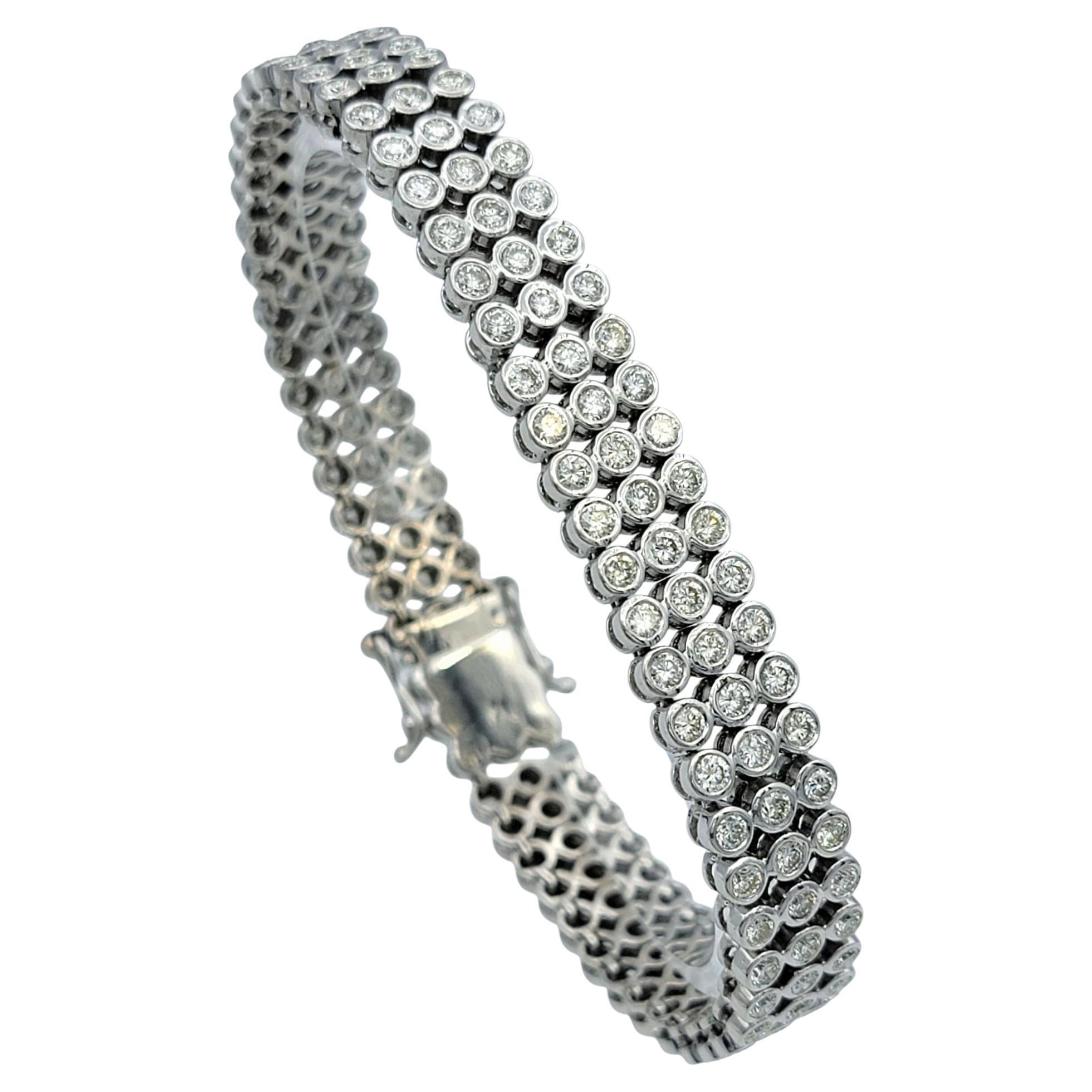 Bold yet refined, this three row diamond tennis bracelet radiates timeless glamour. Each round brilliant cut diamond is meticulously bezel set, creating a continuous shimmer that feels both contemporary and classic. The symmetry of the design