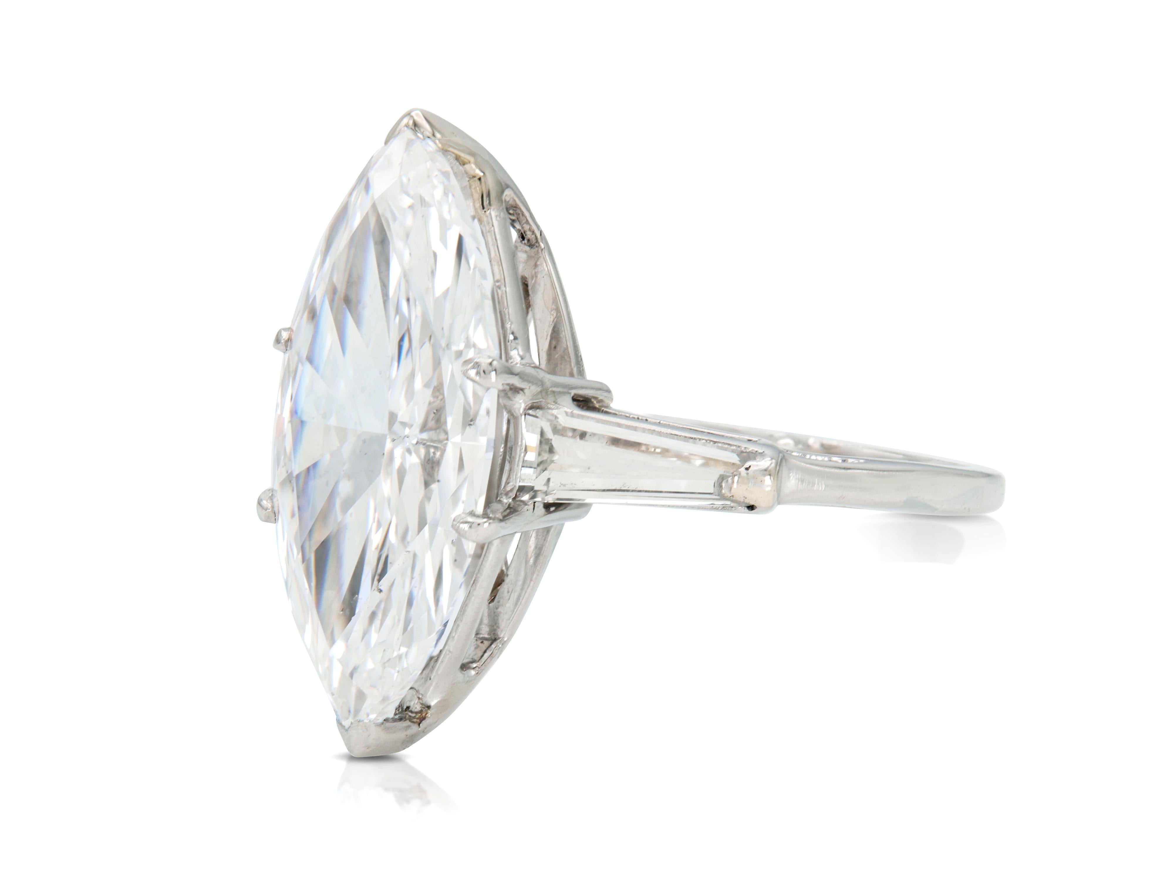 Finamente elaborado en platino con un Diamante central de talla marquesa certificado por el GIA de 6,47 quilates, color D, claridad SI2, GIA #2239235897.
El anillo presenta dos diamantes laterales de talla baguette cónica con un peso total