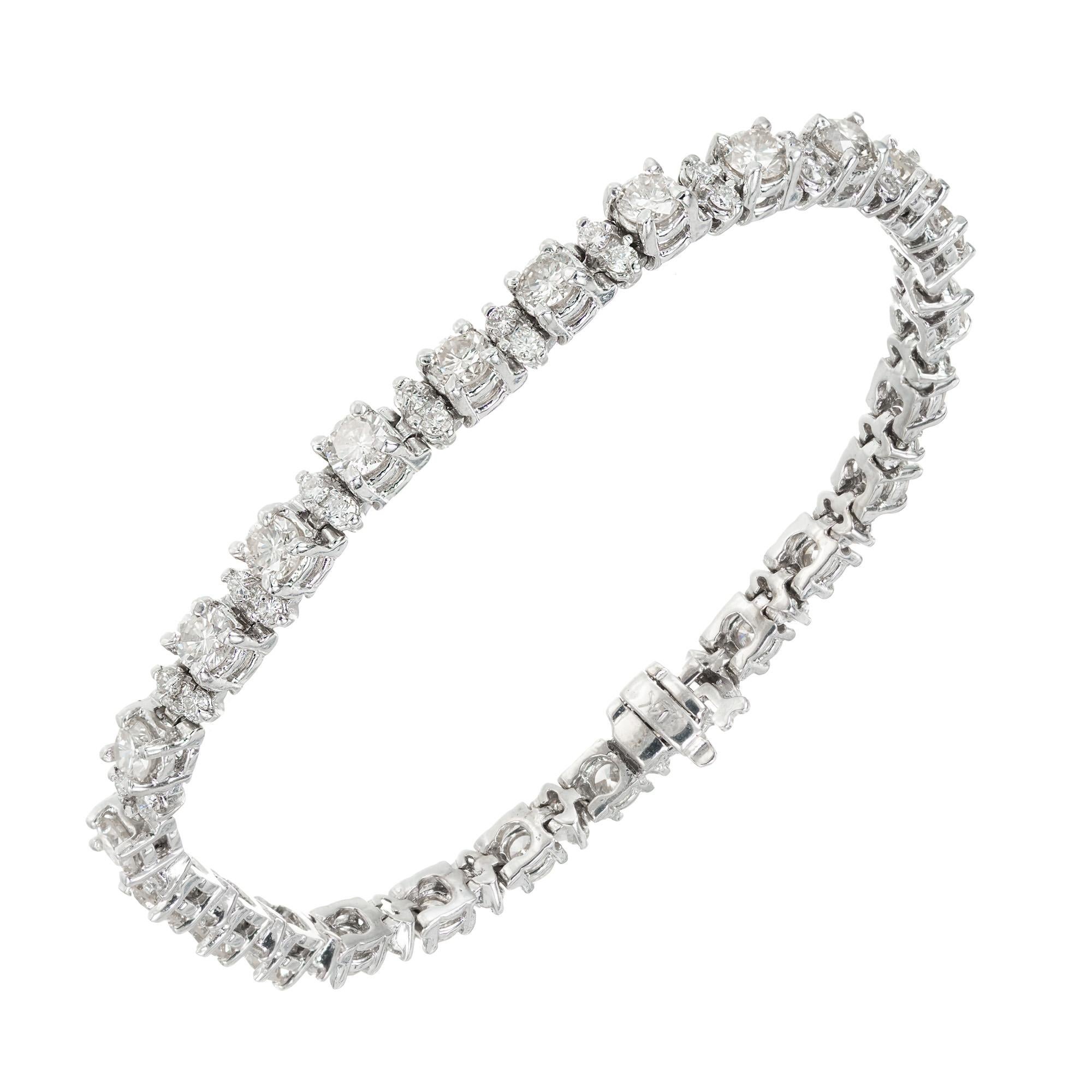 Diamond tennis bracelet. 75 round brilliant cut diamonds set in 14k white gold tennis bracelet. Larger diamonds are each separated with 2 small diamonds. Hinged link bracelet with secure hidden catch and underside safety catch. 7.25 in length. 

25