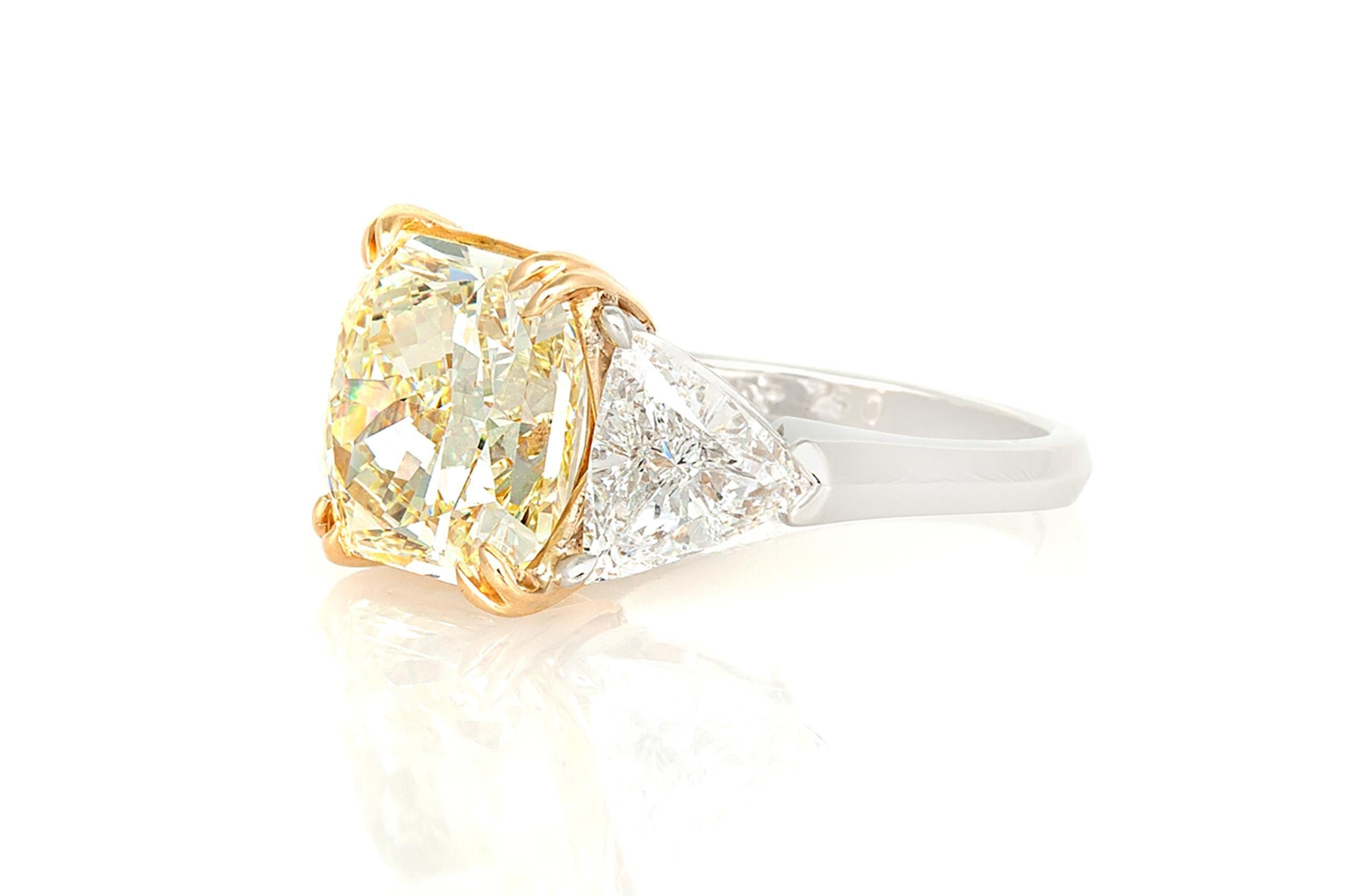 Finely crafted in platinum and 18k yellow gold with a GIA certified Natural Fancy Yellow, Square Radiant cut Diamond weighing 6.75 carats, VVS1 clarity, GIA #2165845082.
The ring features 2 accenting Trillion cut side Diamonds weighing a total of
