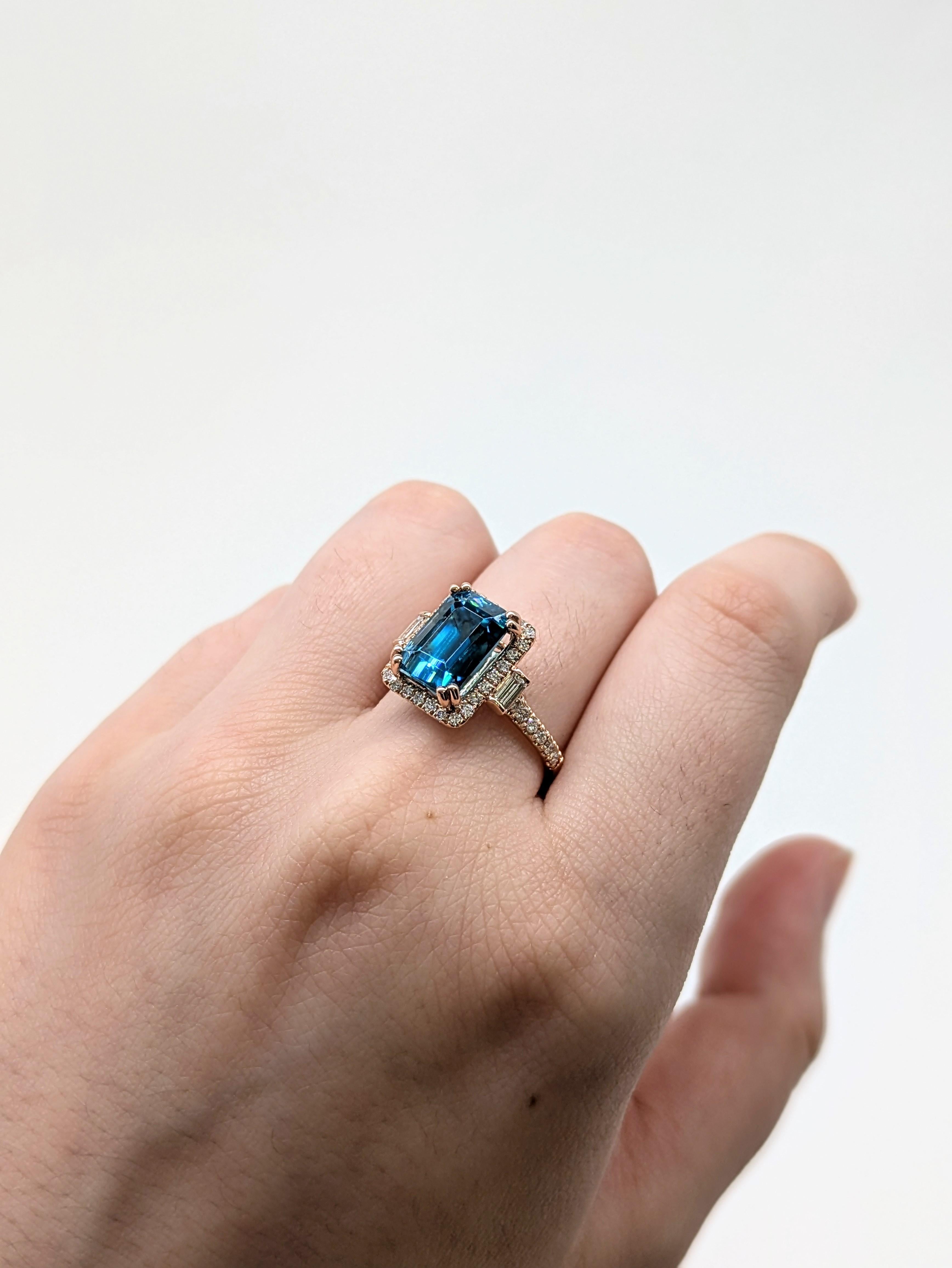 Fai una dichiarazione audace con questo splendido anello con zircone blu da 6,7 carati, incastonato in caldo oro rosa 14 carati. Circondato da un'aureola di diamanti scintillanti estratti dalla terra e accentuato da una brillantezza ancora maggiore