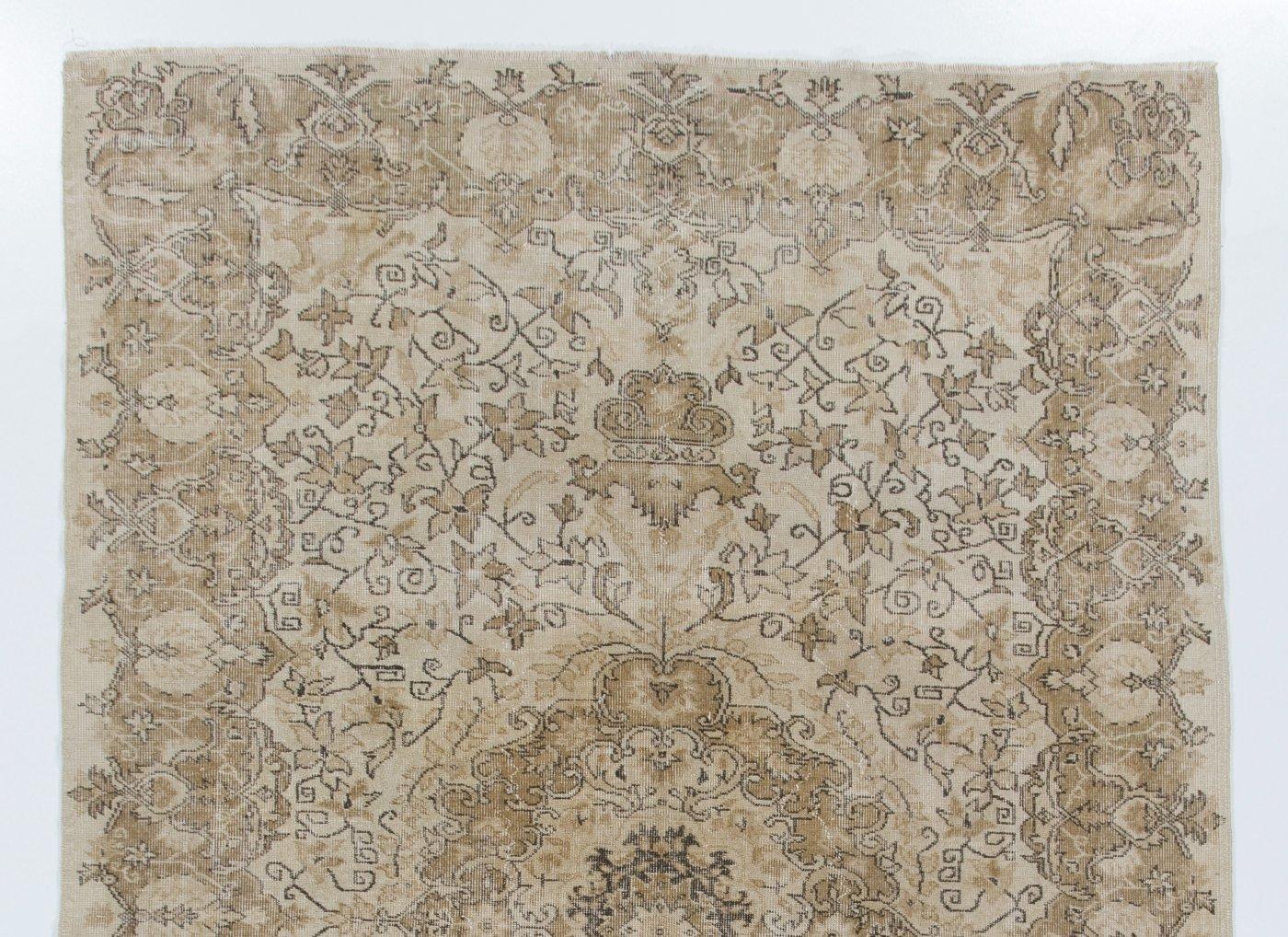 A finely hand-knotted vintage Turkish rug from the 1960s featuring an elegant medallion surrounded all around by lush floral vines and a curvilinear border filled with large rosettes, in beige, khaki and brown. The rug has even low wool pile on