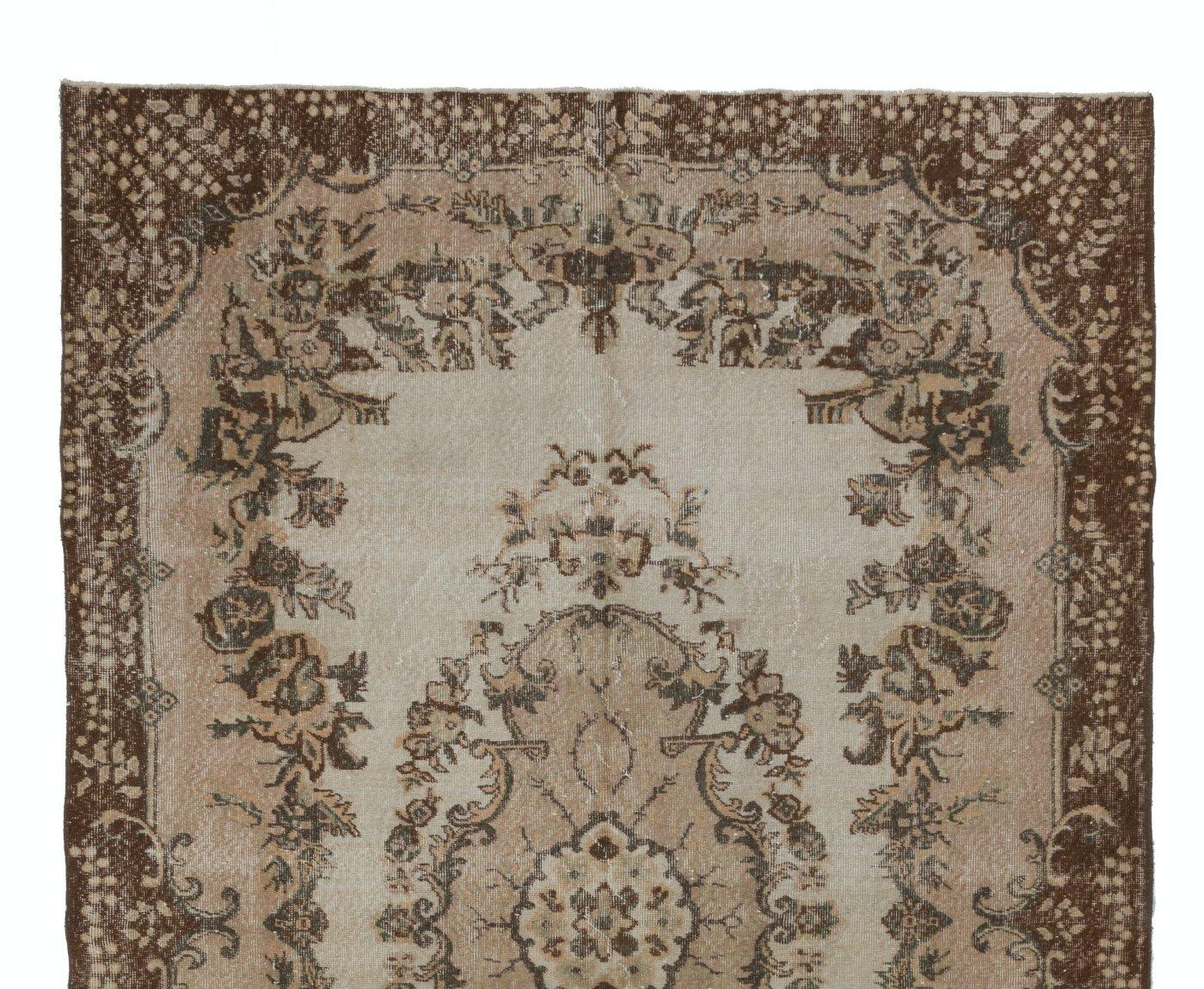 This is a hand-knotted vintage Turkish area rug. The rug features a floral medallion design in a field decorated with floral motifs. It has low distressed wool pile on cotton foundation, is in very good condition, sturdy and clean as a brand new