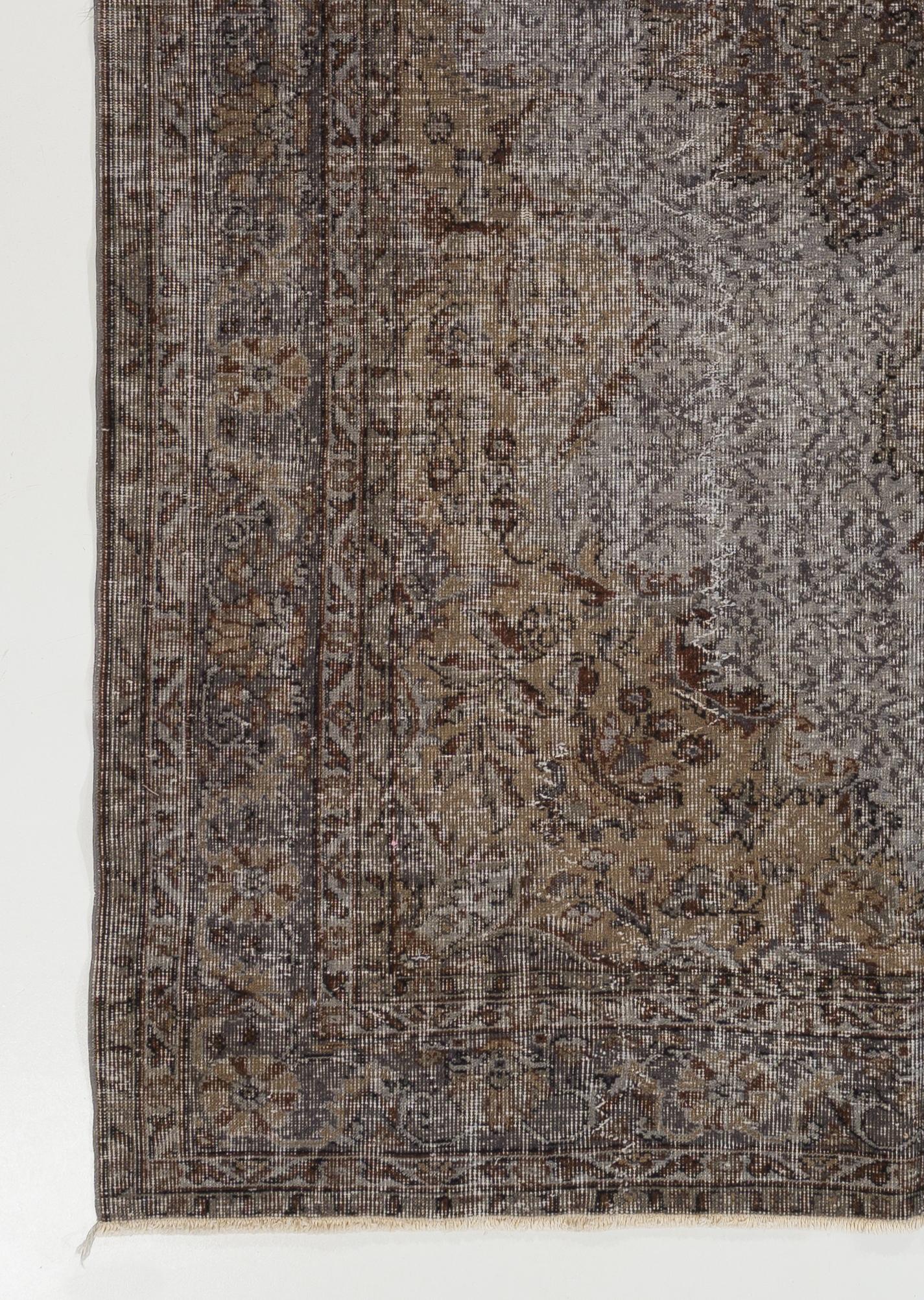 Un tappeto turco vintage tinto in grigio. Il tappeto ha una texture granulosa e affilata e presenta un disegno a medaglione. È finemente annodato a mano con un basso pelo di lana su una base di cotone. È in ottime condizioni, pulito