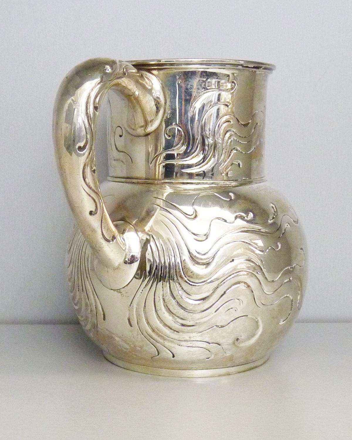 Vintage sterling silver water pitcher. Made by Tiffany & Co. in approximately 1940-1950s. Curved body, flared, rim, waves pattern. Hallmark includes pattern no. 3077 Makers 1380, sterling silver and director’s letter M (1947-1956). 
Capacity 4 1/4