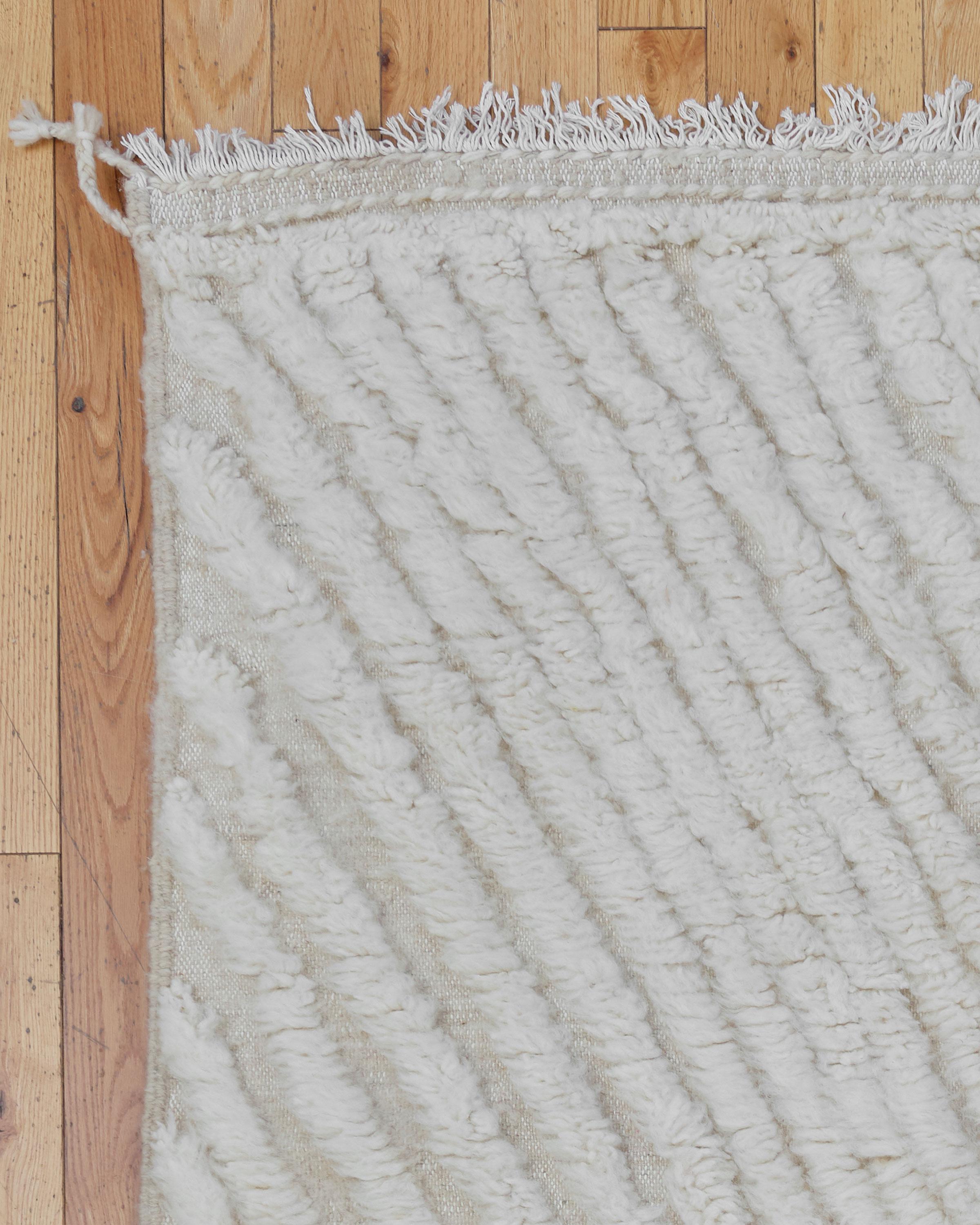 The Alisma rug is a stunning example of traditional Moroccan craftsmanship. Handwoven by Berber artisans in the Atlas Mountains, this luxurious Beni Ouarain rug features a thick, plush wool pile that provides exceptional warmth and comfort. The