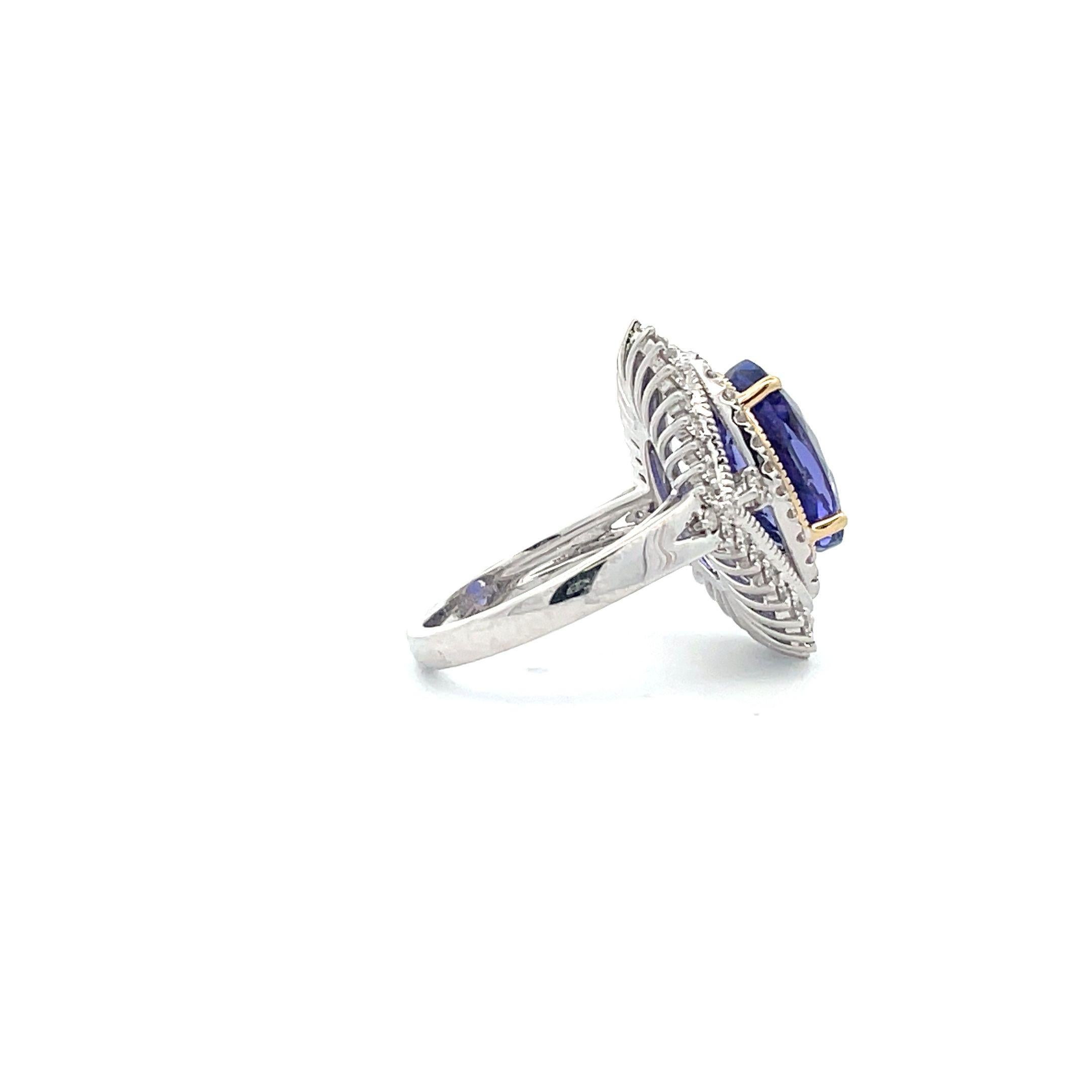 This gorgeous Edwardian-inspired ring is crafted from 6.80 carats of natural Tanzanite, paved, and surrounded by a halo of 64 round diamonds. The setting is meticulously hand-crafted in platinum base metal and finished with 14K White Gold and Yellow