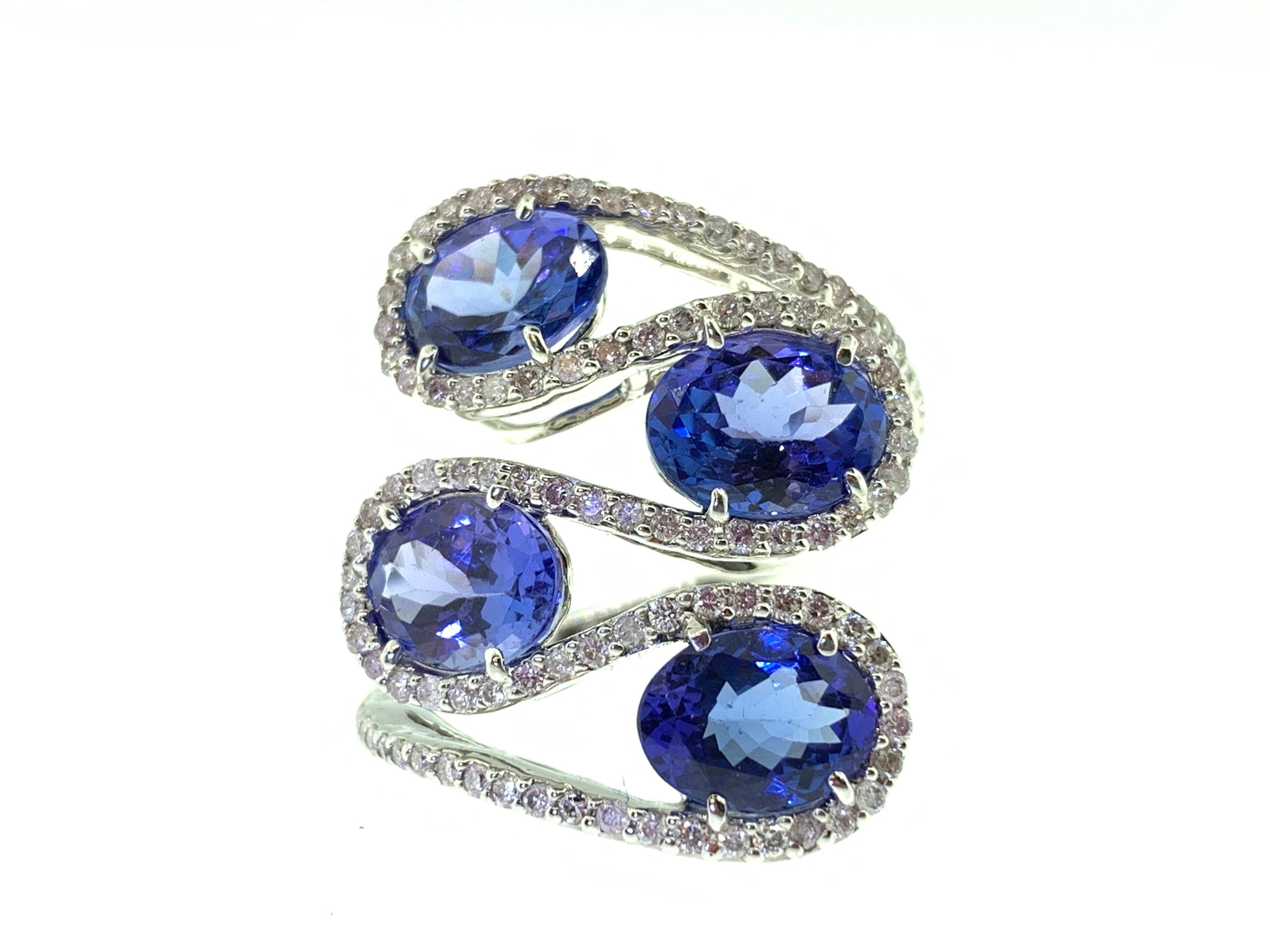This stunningly unique cocktail ring features four Oval Tanzanites (total of 6.82 Carats) surrounded by round diamonds (total of 0.77 Carats). 
This ring is set in 18k White Gold. Ring Size is 6 1/2.