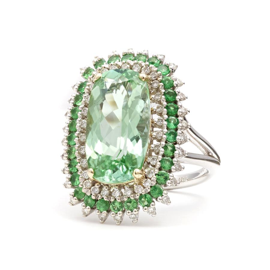 Eye clean and spectacular, this 6.83 carat green tourmaline mined in Namibia will be a great choice to make an impression. Handcrafted in 14K white gold, this ring studded with a halo of diamonds and tsavorites, will take everyone by storm.

Ring