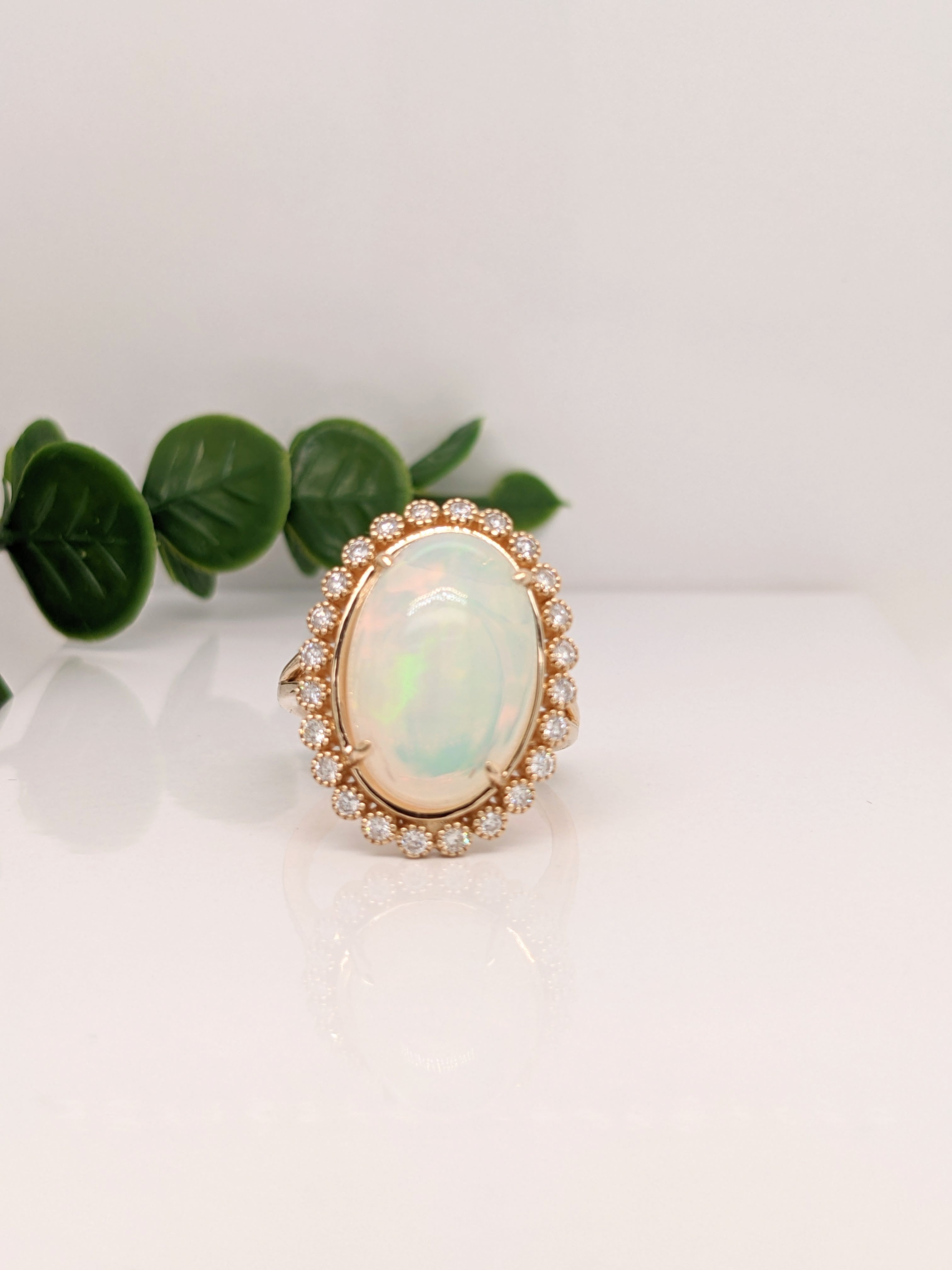 This Welo Opal vintage style ring features a 14K Yellow Gold setting, a full fire Jelly Opal and natural bezel set diamond halo and milgrain. An Art Deco ring design perfect for an eye catching engagement or anniversary. This ring also makes a