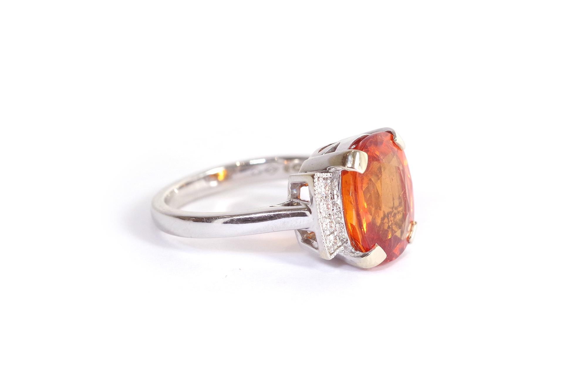 Anello con granato mandarino in oro bianco 18 carati. L'anello è centrato da un granato mandarino ovale (chiamato anche spessartite), dal colore arancione intenso. Il granato pesa circa 6,84 carati. Il granato è incastonato con quattro griffe e